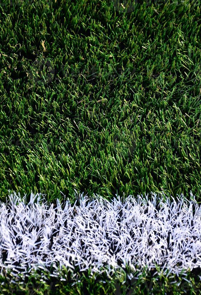 White stripe on a bright green artificial grass soccer field photo