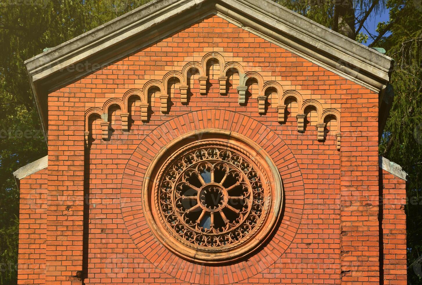 Texture front part of an ancient brick crypt with a round patterned carved window in the cemetery photo