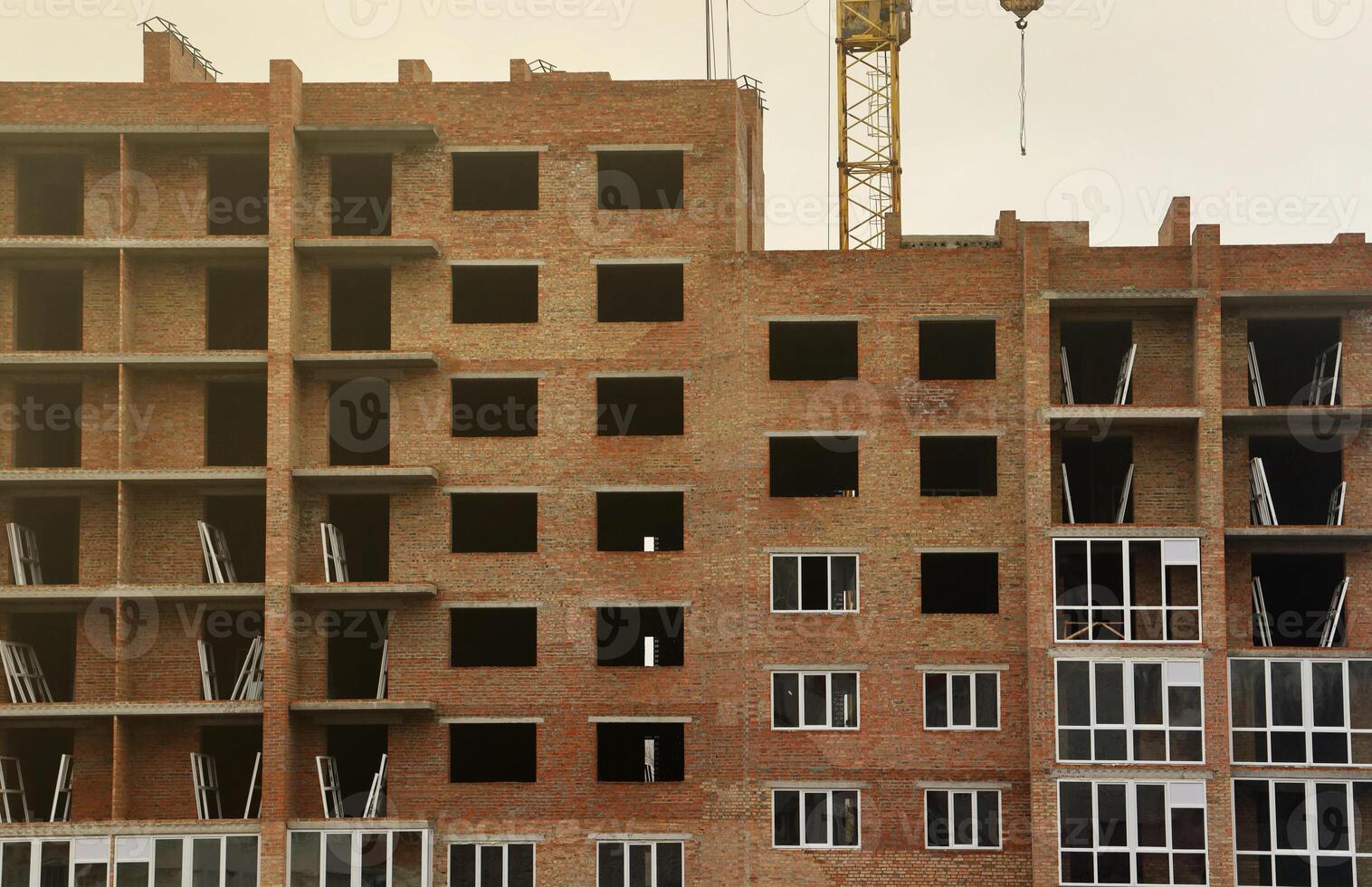 View of a large construction site with buildings under construction and multi-storey residential homes. Tower cranes in action on blue sky background. Housing renovation concept photo