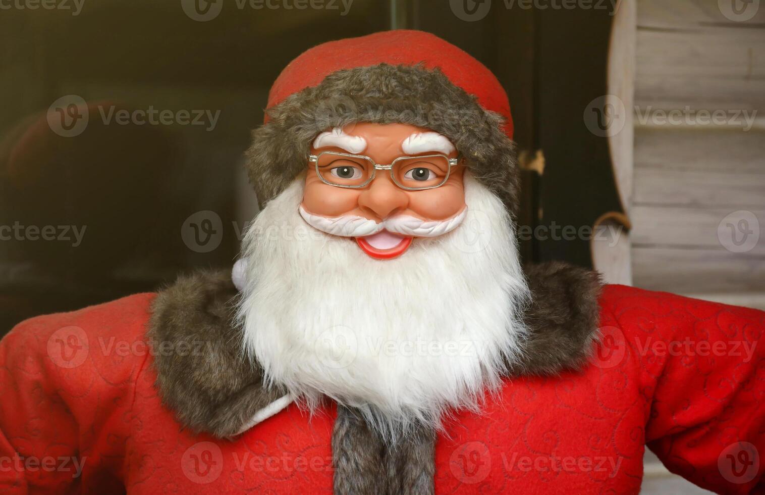 Santa claus big plastic figure with classic santa clothes close to wooden house photo