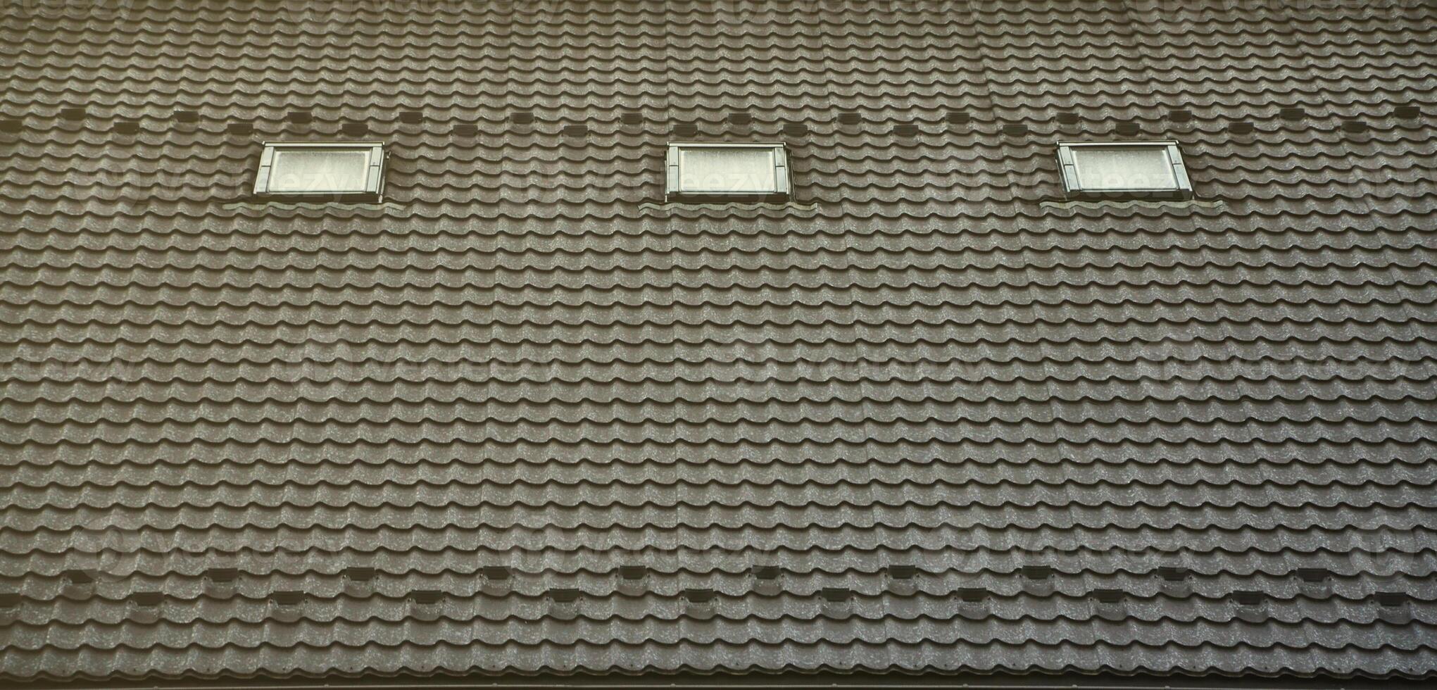 The texture of the roof with a roof made of metal, covered with drops from the rain. Several pane windows are built into the roof photo