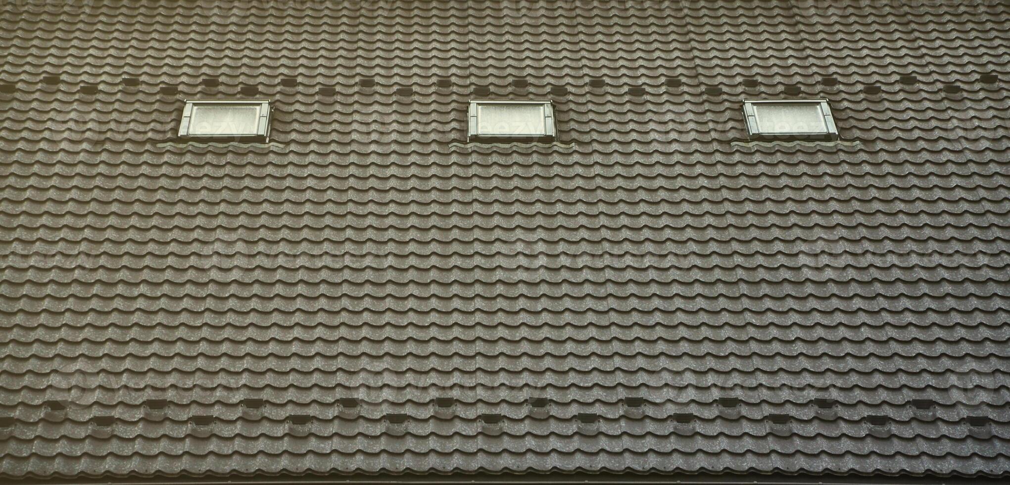 The texture of the roof with a roof made of metal, covered with drops from the rain. Several pane windows are built into the roof photo