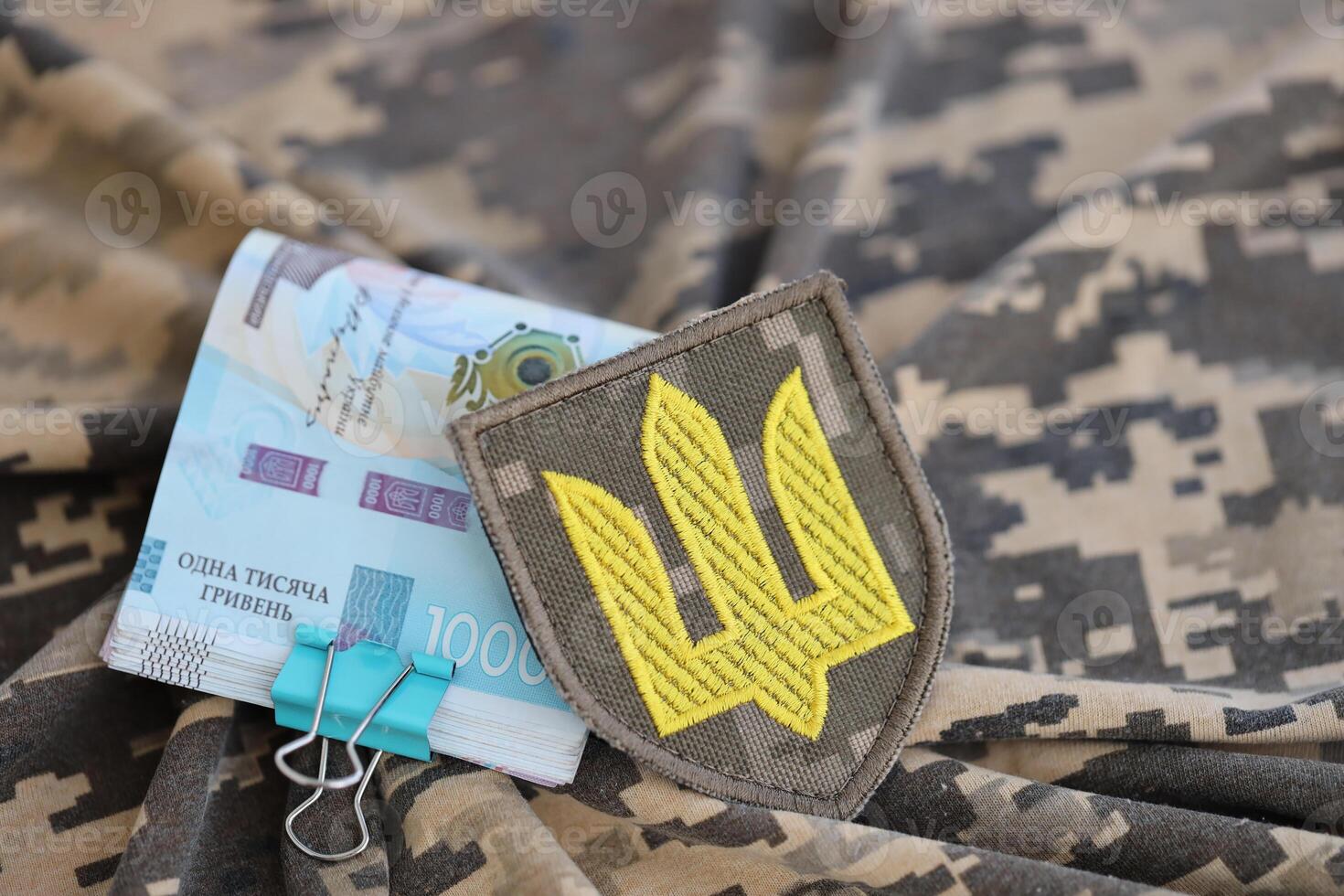 Ukrainian army symbol and bunch of hryvnia bills on military uniform. Payments to soldiers of the Ukrainian army, salaries to the military photo