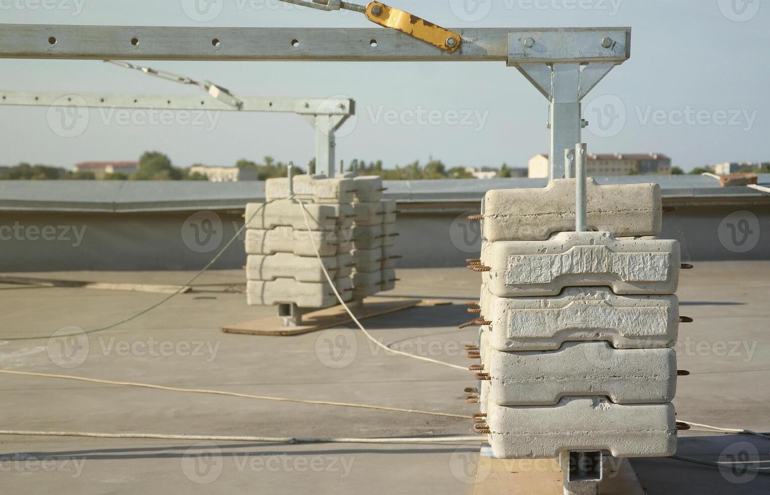 Counter weight or weight balance concrete blocks or bricks as part of suspended wire rope platform for facade works on high multistorey buildings. Many blocks with metal handles photo