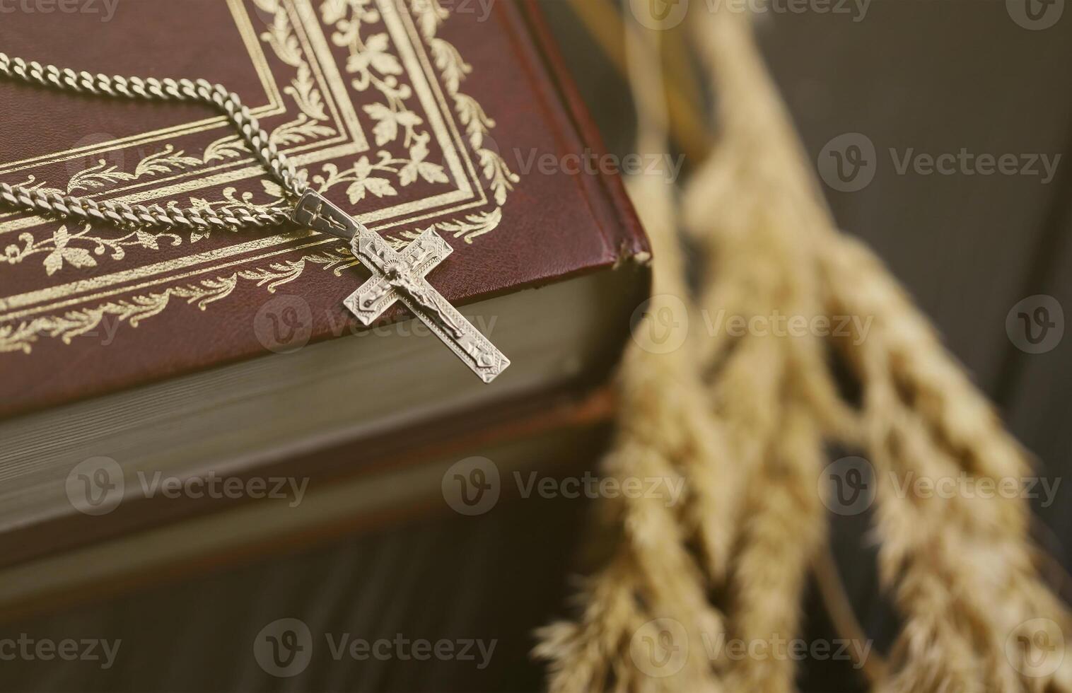 Silver necklace with crucifix cross on christian holy bible book on black wooden table. Asking blessings from God with the power of holiness photo