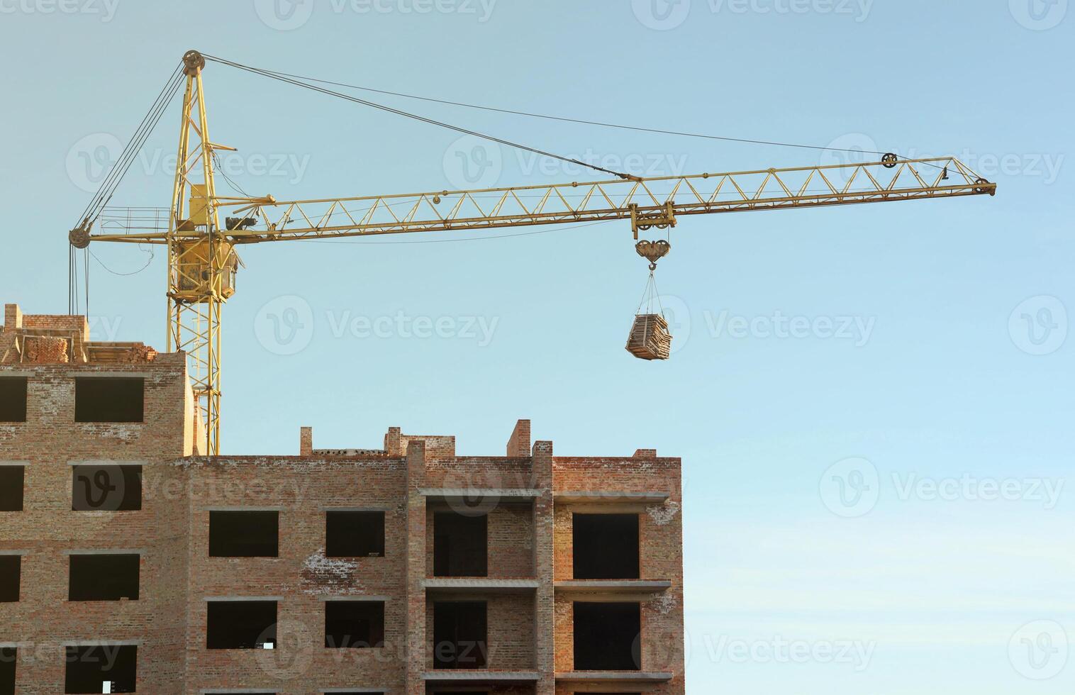 View of a large construction site with buildings under construction and multi-storey residential homes. Tower cranes in action on blue sky background. Housing renovation concept photo