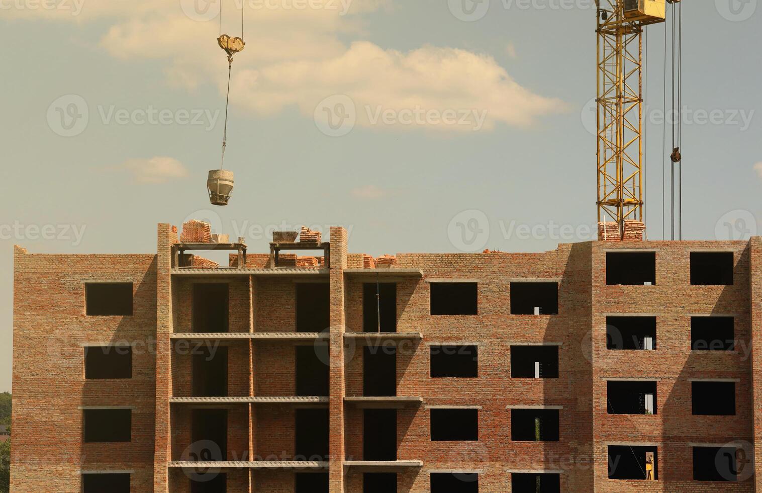 View of a large construction site with buildings under construction and multi-storey residential homes. Tower cranes in action on blue sky background. Housing renovation concept photo