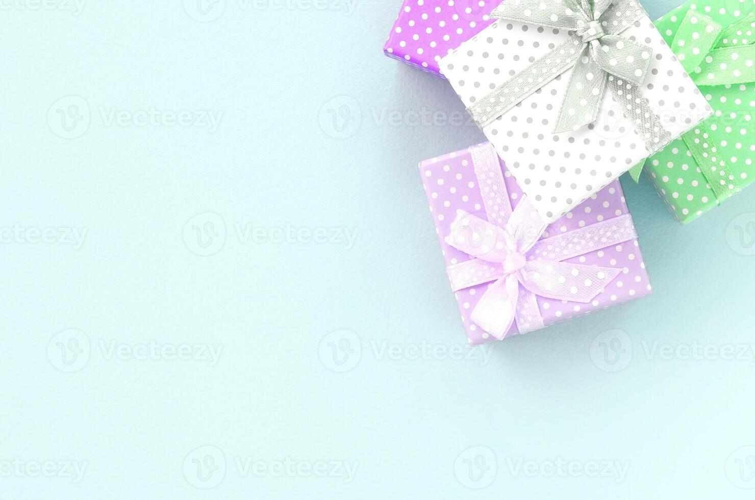 Pile of a small colored gift boxes with ribbons lies on a violet background. Minimalism flat lay top view photo