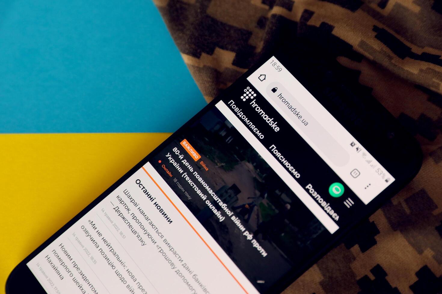 KYIV, UKRAINE - 4 MAY, 2023 Hromadske ukrainian news portal on smartphone screen with ukrainian flag and camouflage fabric photo