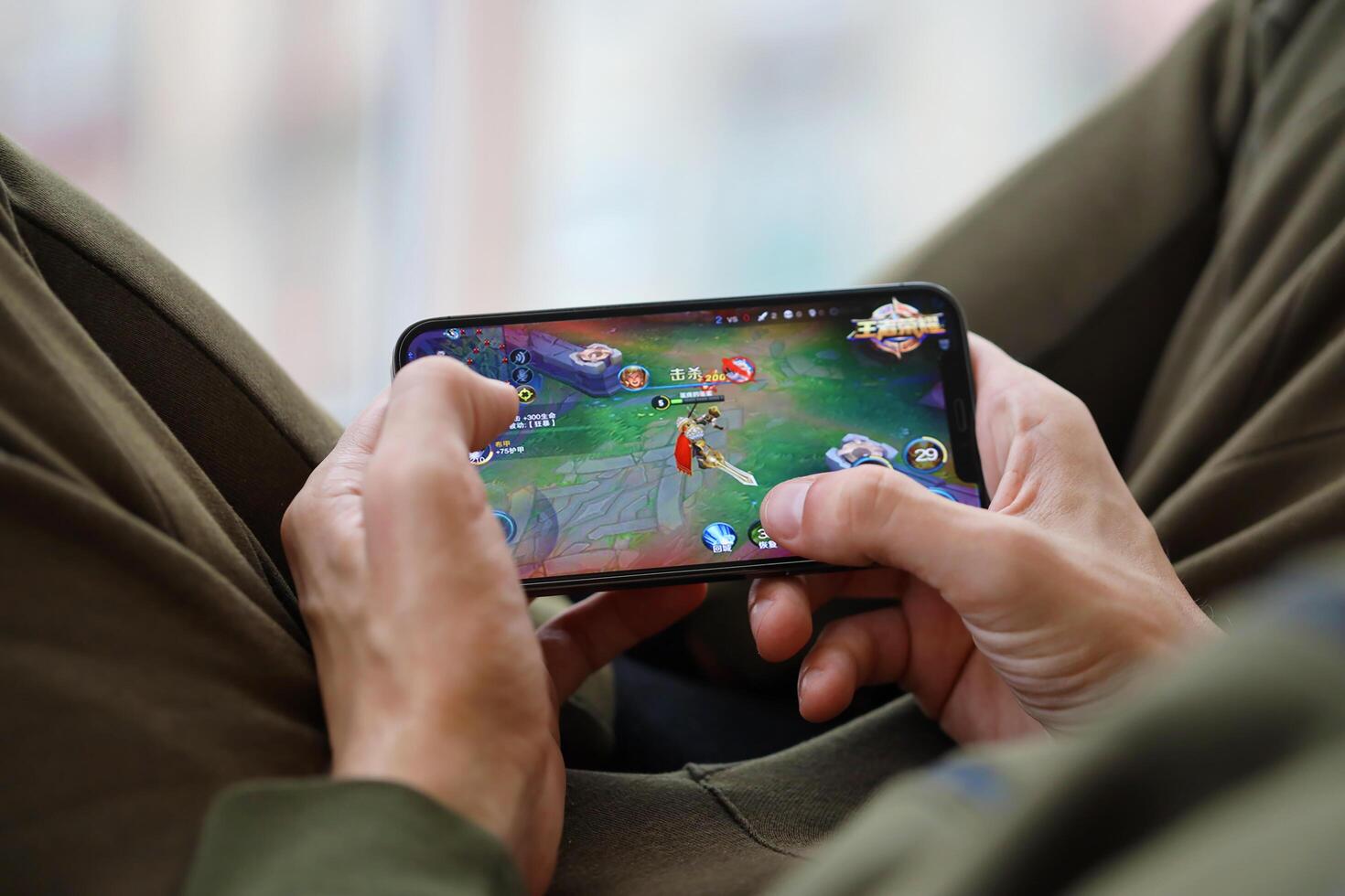 Honor of Kings mobile iOS game on iPhone 15 smartphone screen in male hands during mobile gameplay photo