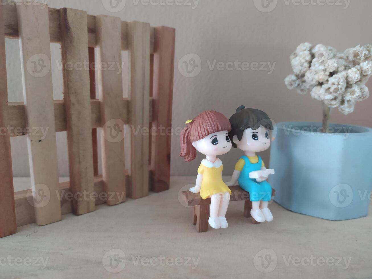 a couple of figurines sitting on a wooden bench photo