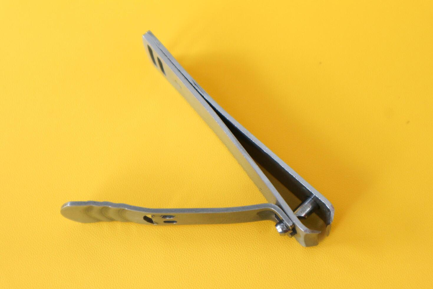 Stainless steel nail clippers isolated on yellow background photo