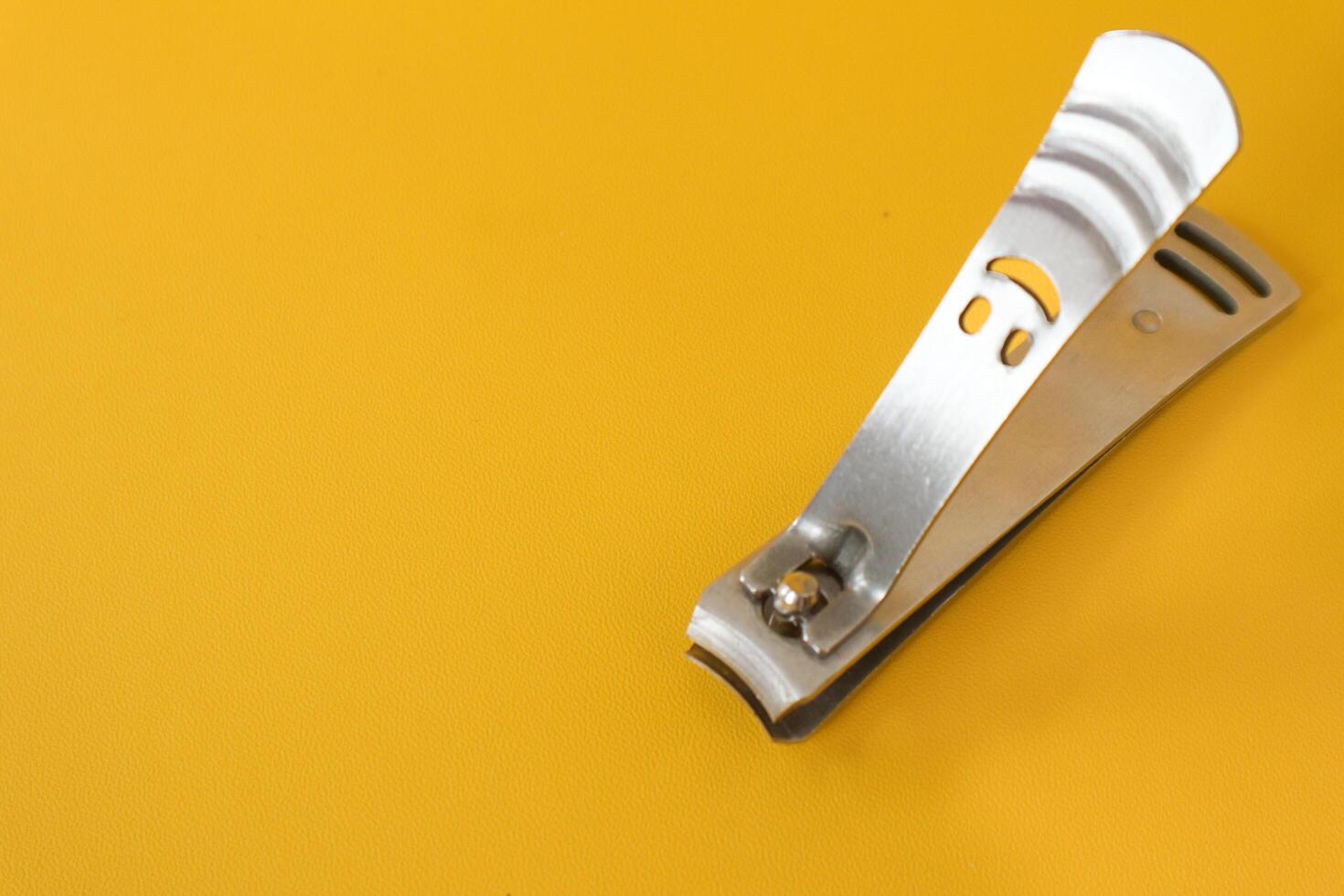 Stainless steel nail clippers isolated on yellow background photo