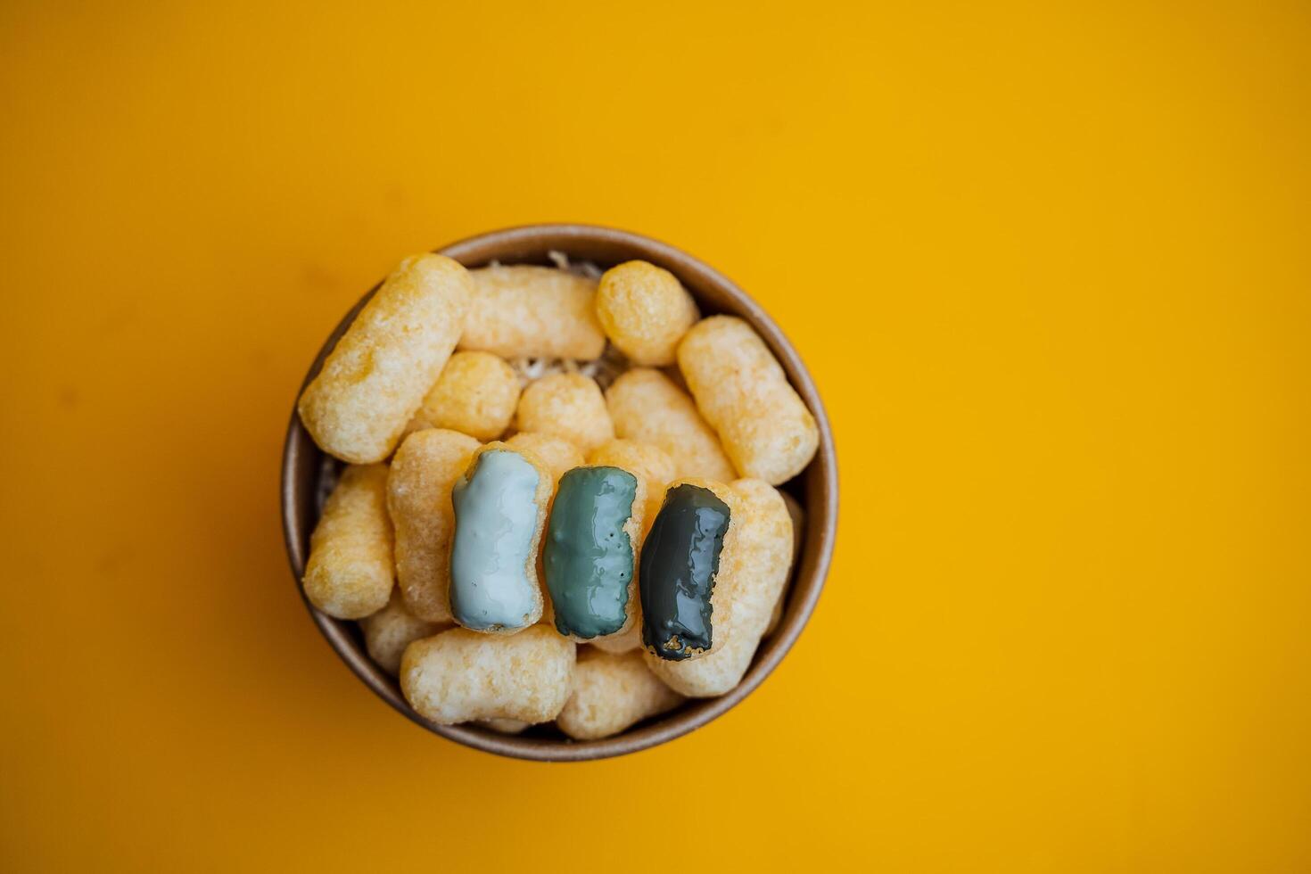 cans of paint on a colored background, shades of green, sweet corn lying in a can of paint, top view, minimalism concept, object on a yellow background close-up photo