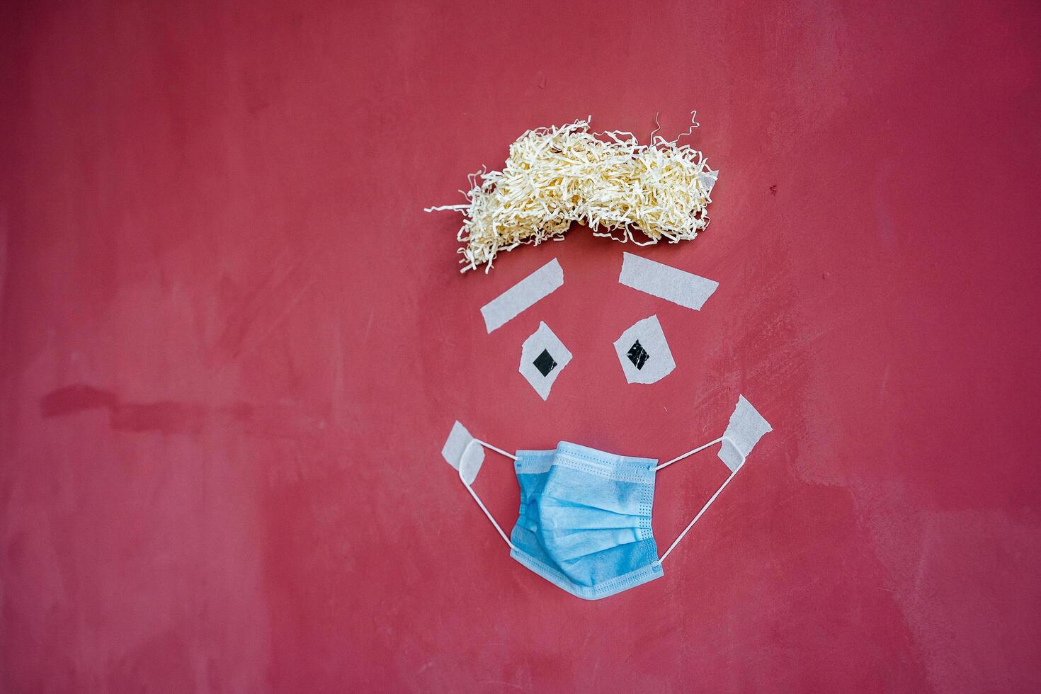 visual art of the image of a person's face on the wall, creative approach to the image of a patient in a mask, protective medical mask in a minimalistic concept, drawing on a maroon wall photo