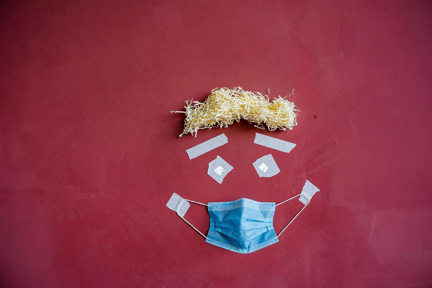 visual art of the image of a person's face on the wall, creative approach to the image of a patient in a mask, protective medical mask in a minimalistic concept, drawing on a maroon wall photo