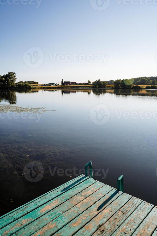 de madera muelle en el lago. calma agua superficie reflexión. muelle en el agua. verano es el silencio de el agua naturaleza. el belleza de naturaleza. paz. minimalismo un sitio a nadar. foto