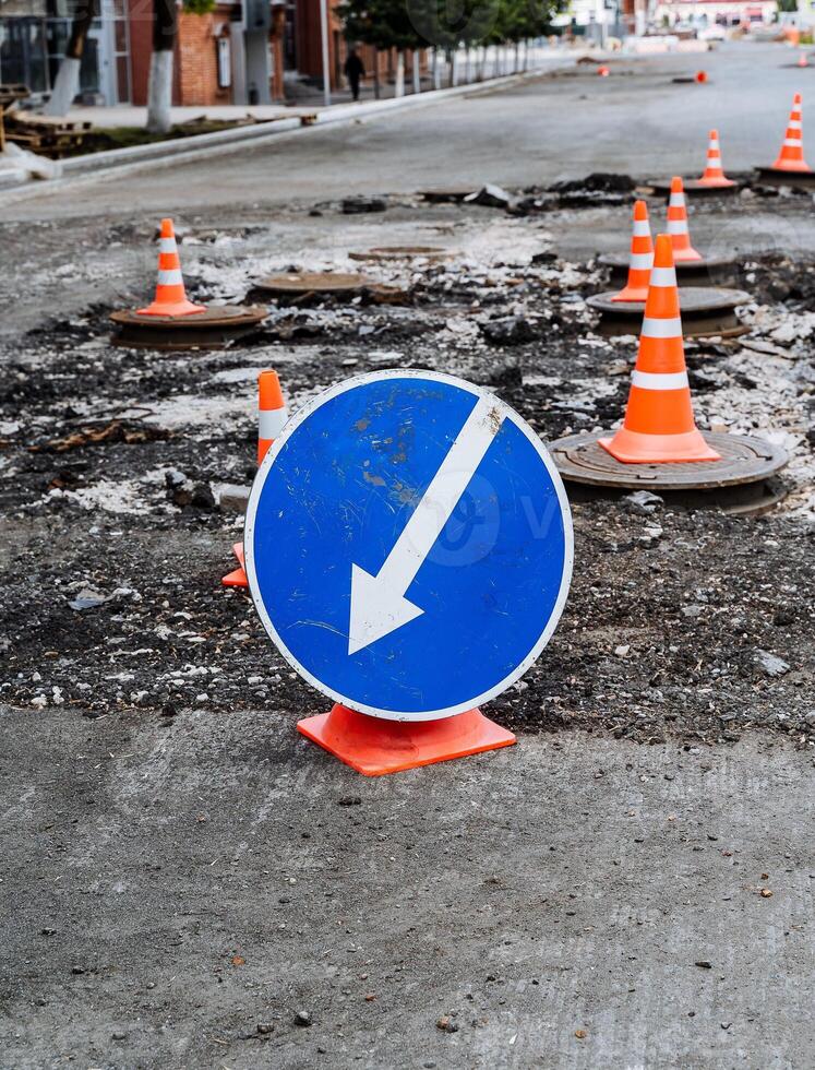 la carretera firmar un blanco flecha en un azul antecedentes indica el camino, la carretera obras, desvío de un peligroso sección de camino, reparar de el firme foto