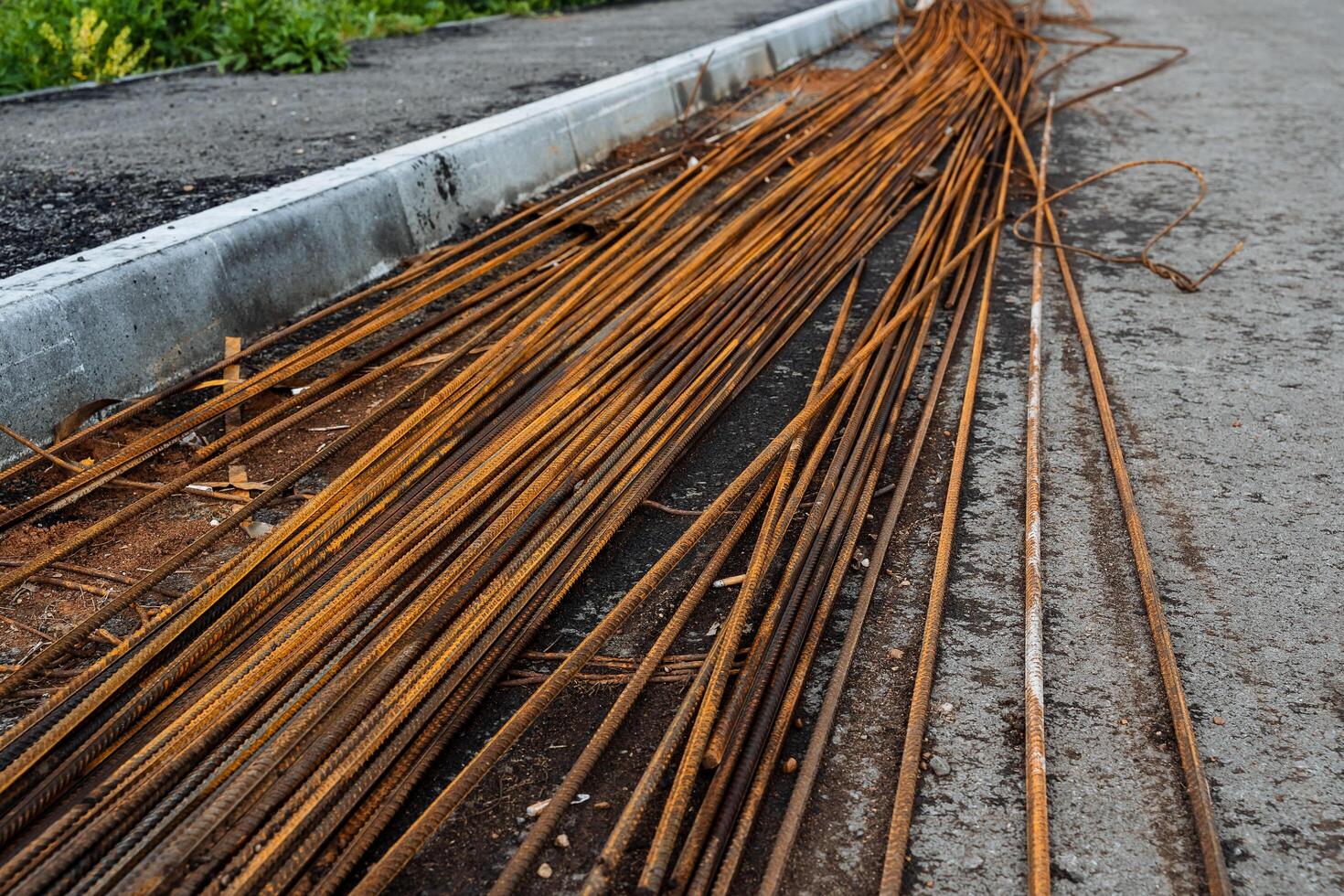 rebar for construction is lying on the asphalt, a pile of rusty rods, metal rods orange color photo