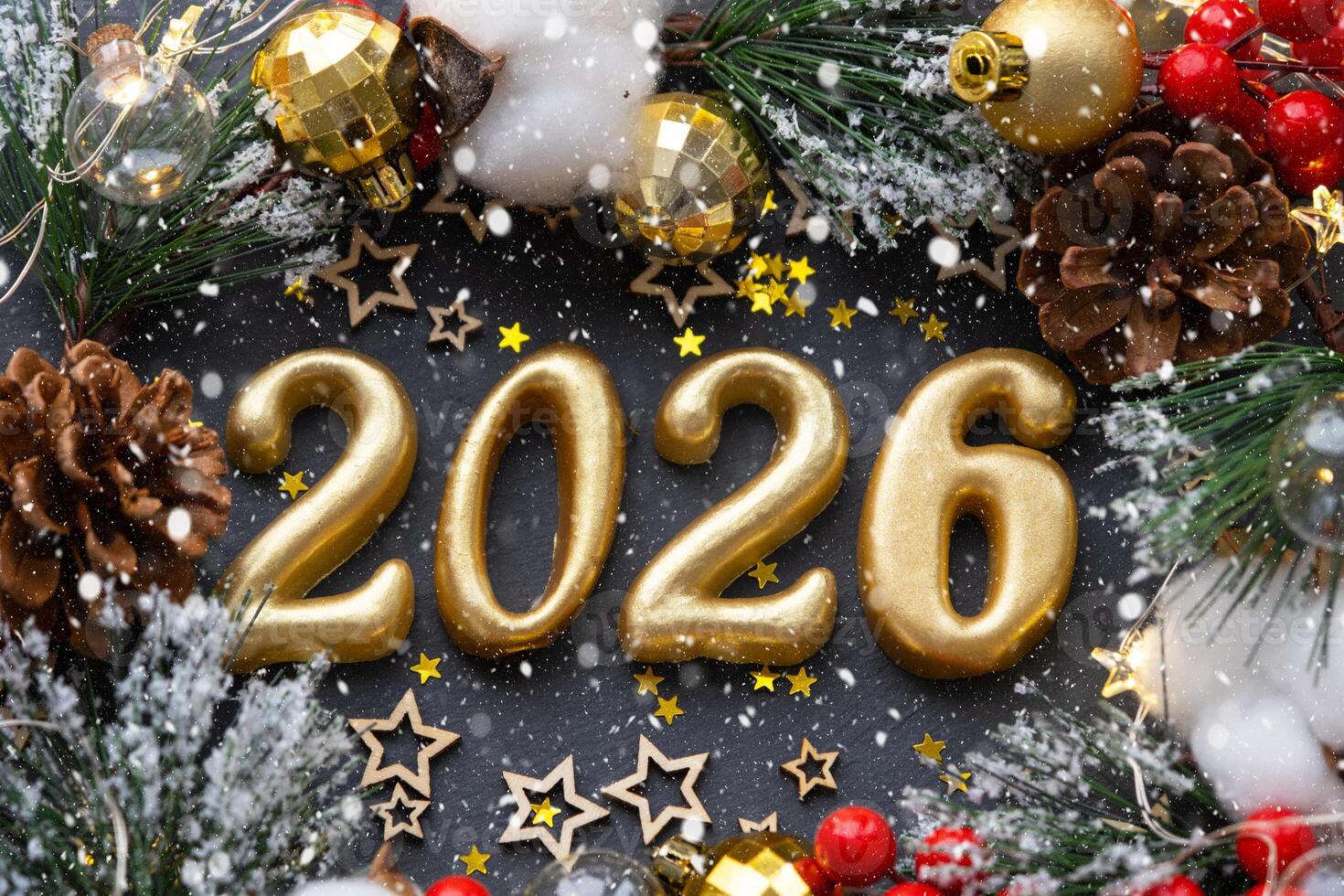 The golden figures 2026 made of candles on a black stone slate background are decorated with a festive decor of stars, sequins, fir branches, balls and garlands. Greeting card, happy New Year. photo