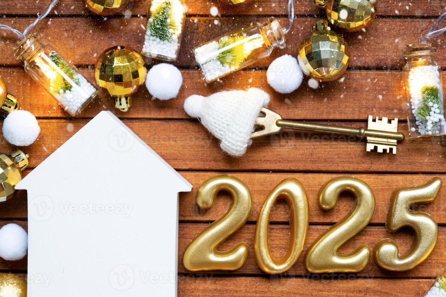 House key with tiny figure of home mock up on festive brown wooden background, lights of garlands. New Year 2025 wooden letters, greeting card. Purchase, construction, relocation, mortgage, insurance photo