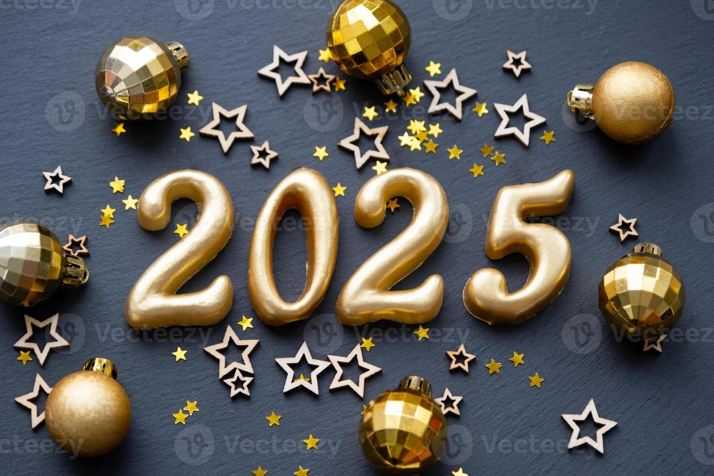 The golden figures 2025 made of candles on a black stone slate background are decorated with a festive decor of stars, sequins, fir branches, balls and garlands. Greeting card, happy New Year. photo