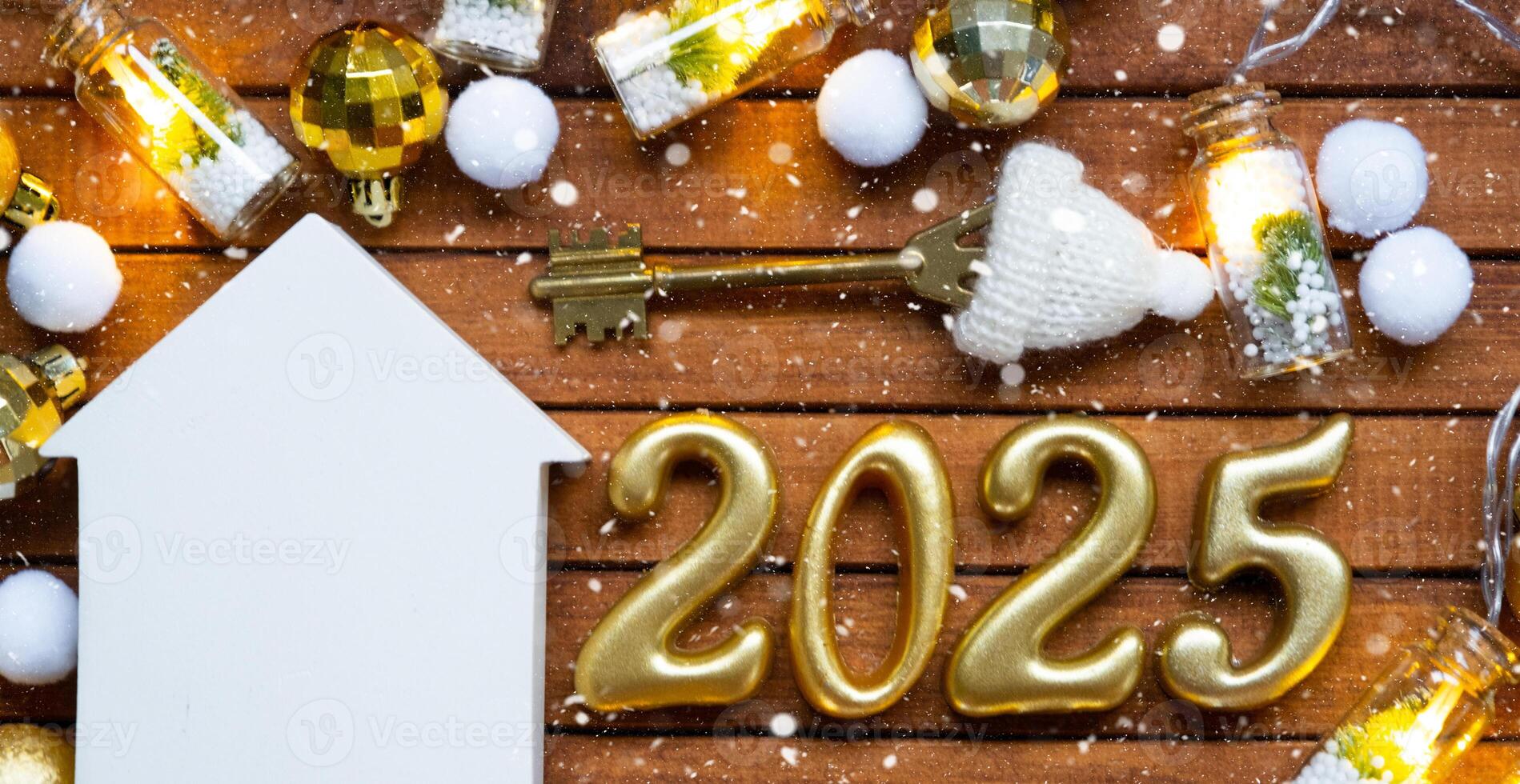 House key with tiny figure of home mock up on festive brown wooden background, lights of garlands. New Year 2025 wooden letters, greeting card. Purchase, construction, relocation, mortgage, insurance photo