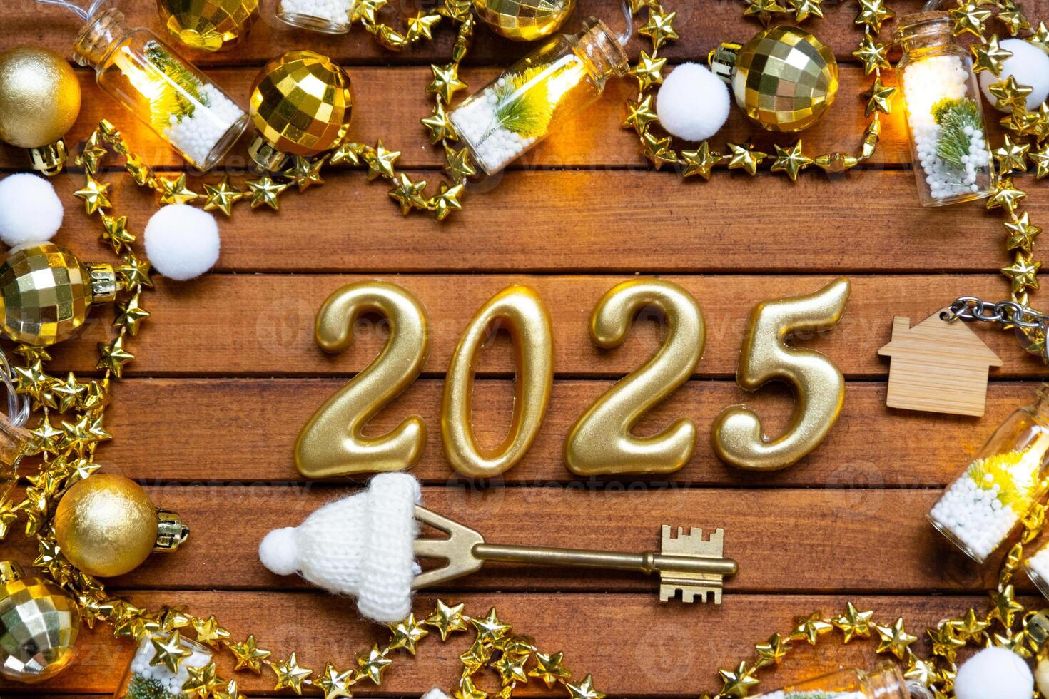 House key with tiny figure of home mock up on festive brown wooden background, lights of garlands. New Year 2025 wooden letters, greeting card. Purchase, construction, relocation, mortgage, insurance photo