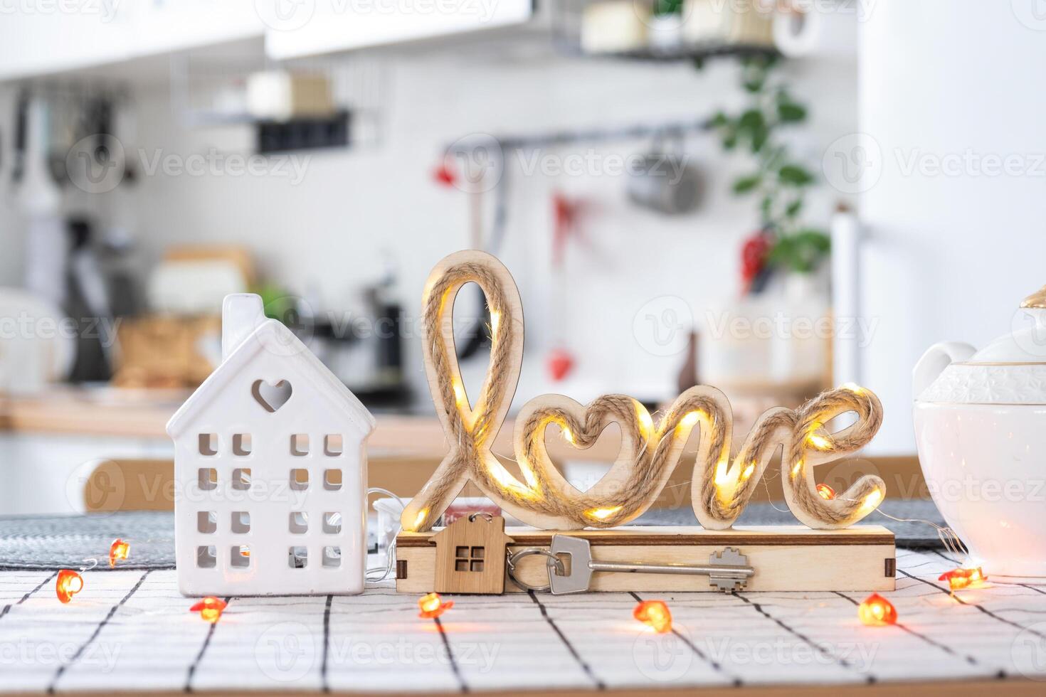 Key to tiny house of cozy home with Valentine decor on table of kitchen. Gift for valentines day, family love nest. design, project, moving to new house, mortgage, rent and purchase real estate photo