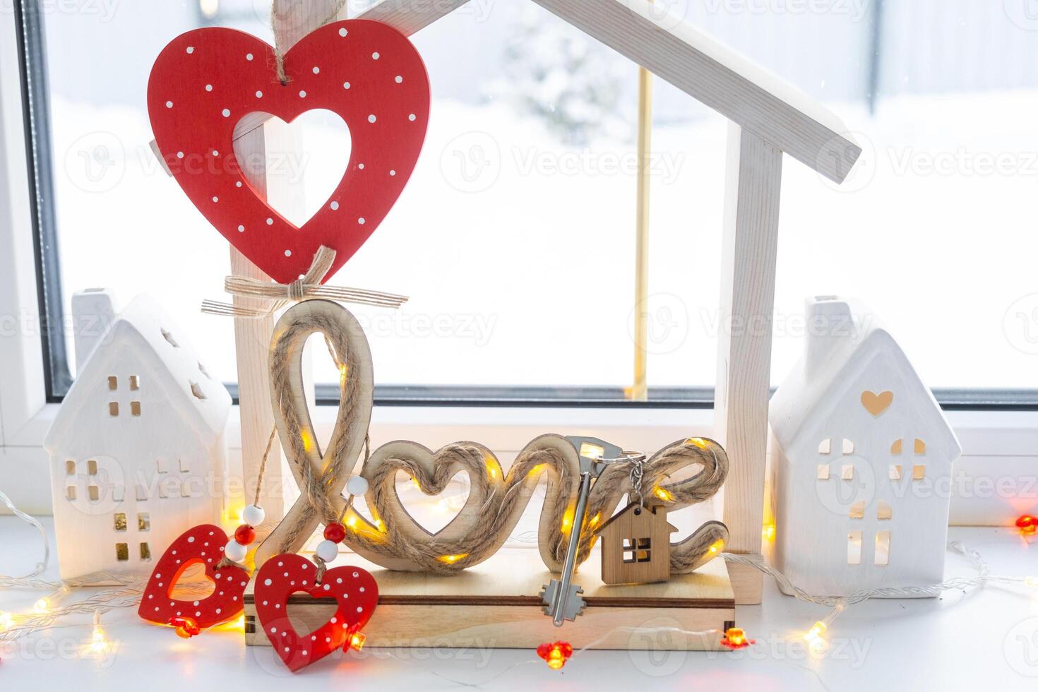 Key to tiny house of cozy home with Valentine decor on the windowsill. Gift for valentines day, family love nest. design, project, moving to new house, mortgage, rent and purchase real estate photo