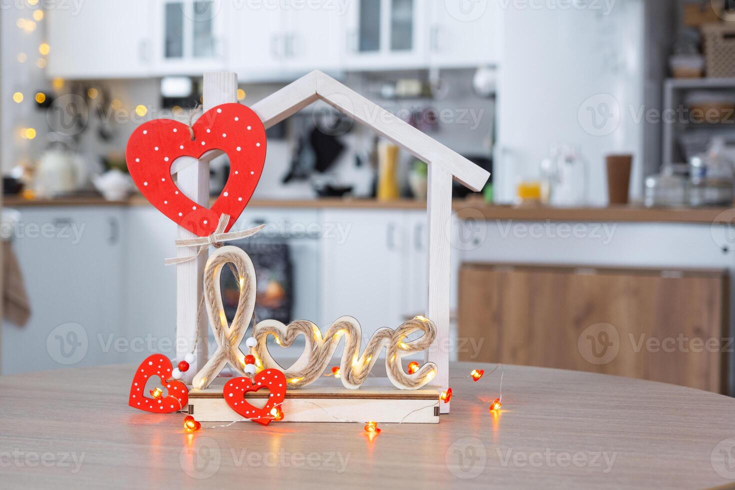 Key to tiny house of cozy home with Valentine decor on table of kitchen. Gift for valentines day, family love nest. design, project, moving to new house, mortgage, rent and purchase real estate photo