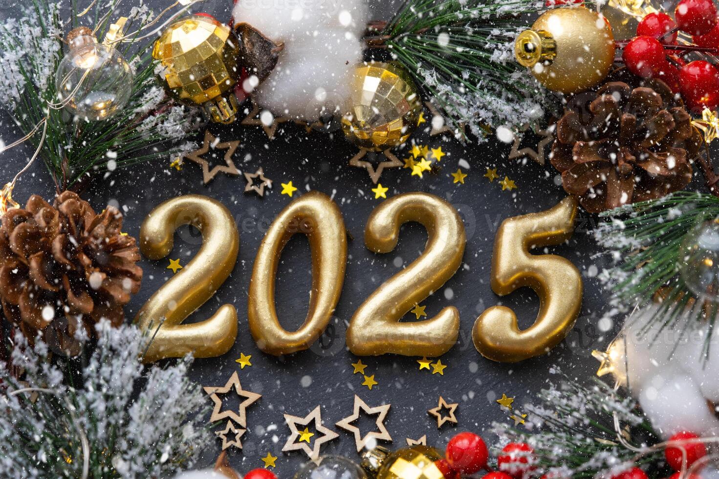 The golden figures 2025 made of candles on a black stone slate background are decorated with a festive decor of stars, sequins, fir branches, balls and garlands. Greeting card, happy New Year. photo