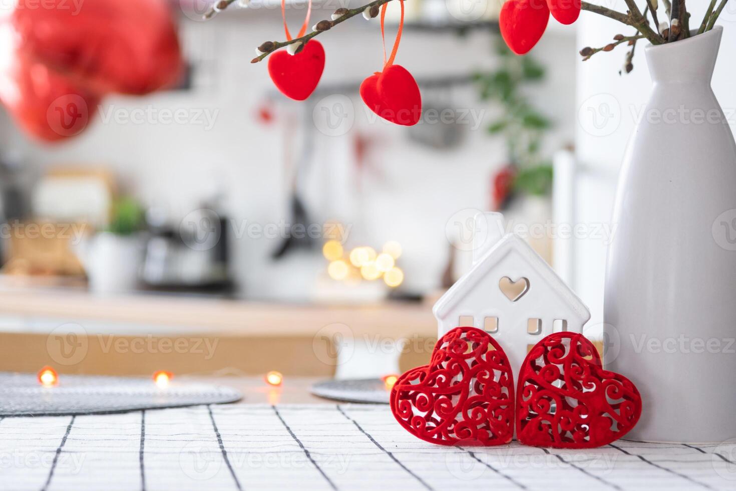 Key to tiny house of cozy home with Valentine decor on table of kitchen. Gift for valentines day, family love nest. design, project, moving to new house, mortgage, rent and purchase real estate photo