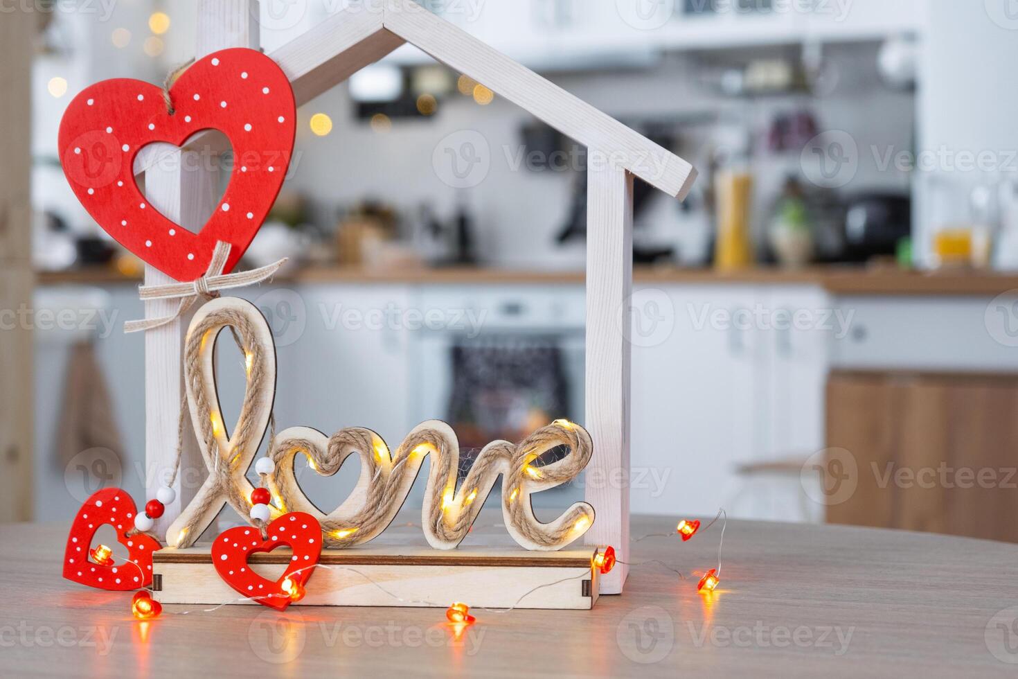 Key to tiny house of cozy home with Valentine decor on table of kitchen. Gift for valentines day, family love nest. design, project, moving to new house, mortgage, rent and purchase real estate photo