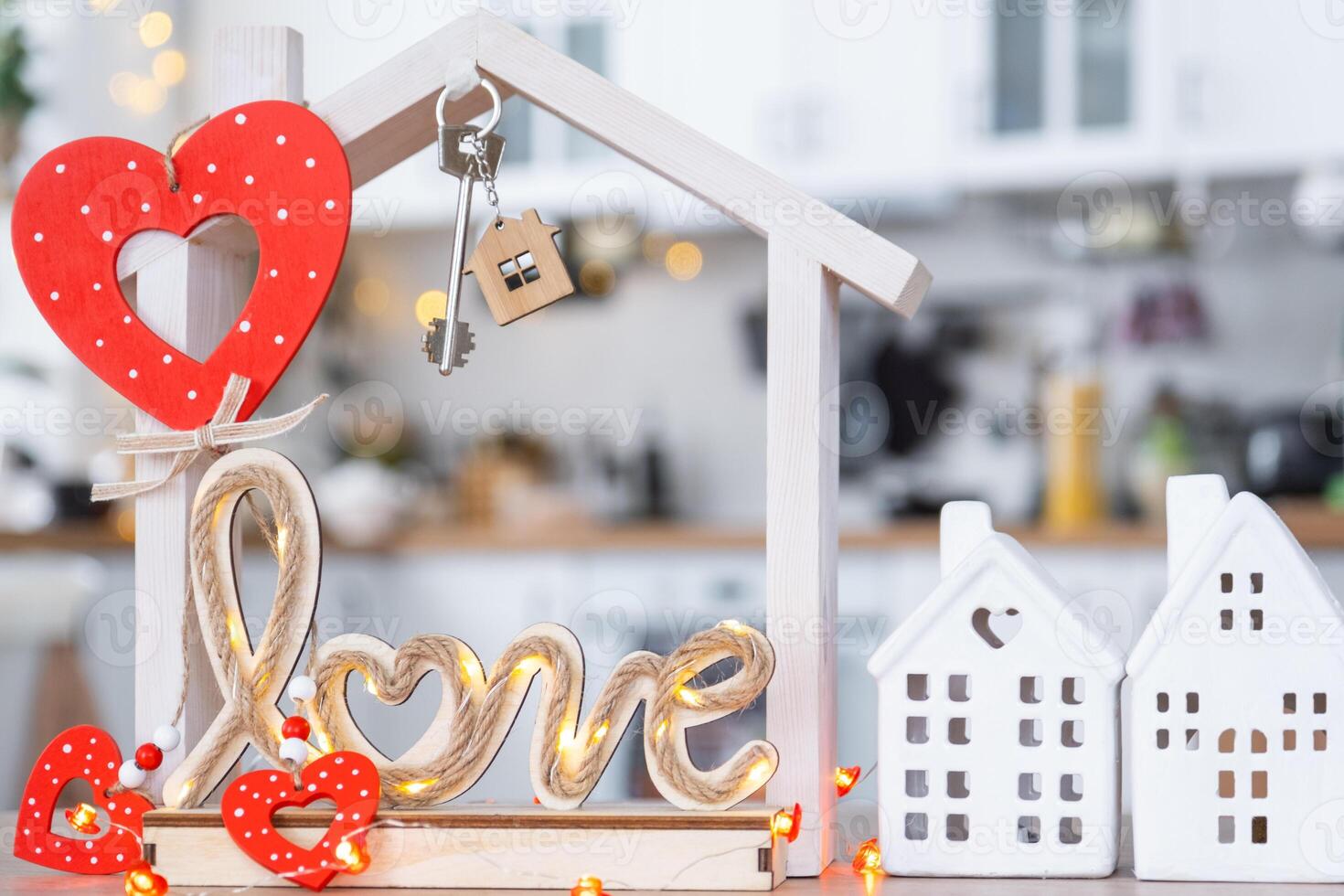 Key to tiny house of cozy home with Valentine decor on table of kitchen. Gift for valentines day, family love nest. design, project, moving to new house, mortgage, rent and purchase real estate photo