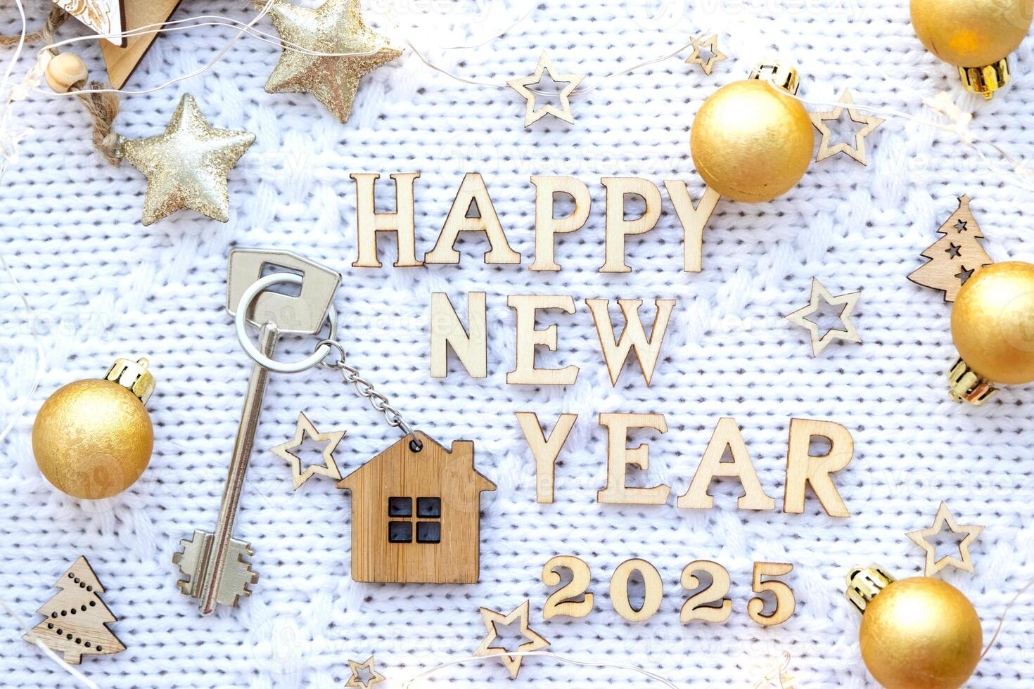 House key with keychain cottage on festive background with stars, lights of garlands. New Year 2025 wooden letters, greeting card. Purchase, construction, relocation, mortgage, insurance photo