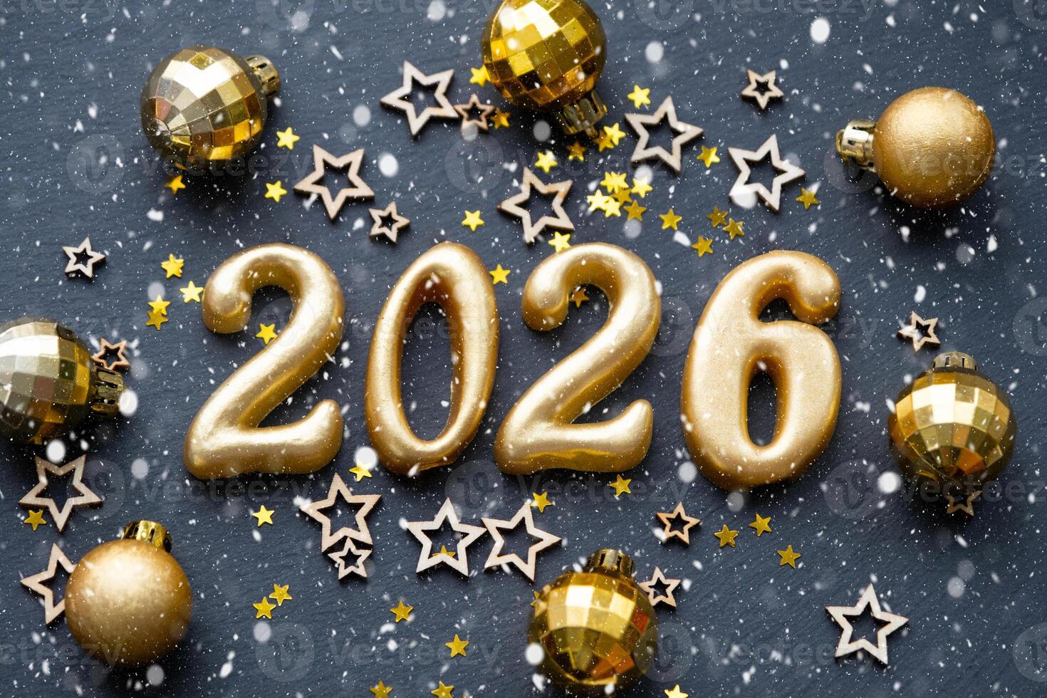 The golden figures 2026 made of candles on a black stone slate background are decorated with a festive decor of stars, sequins, fir branches, balls and garlands. Greeting card, happy New Year. photo