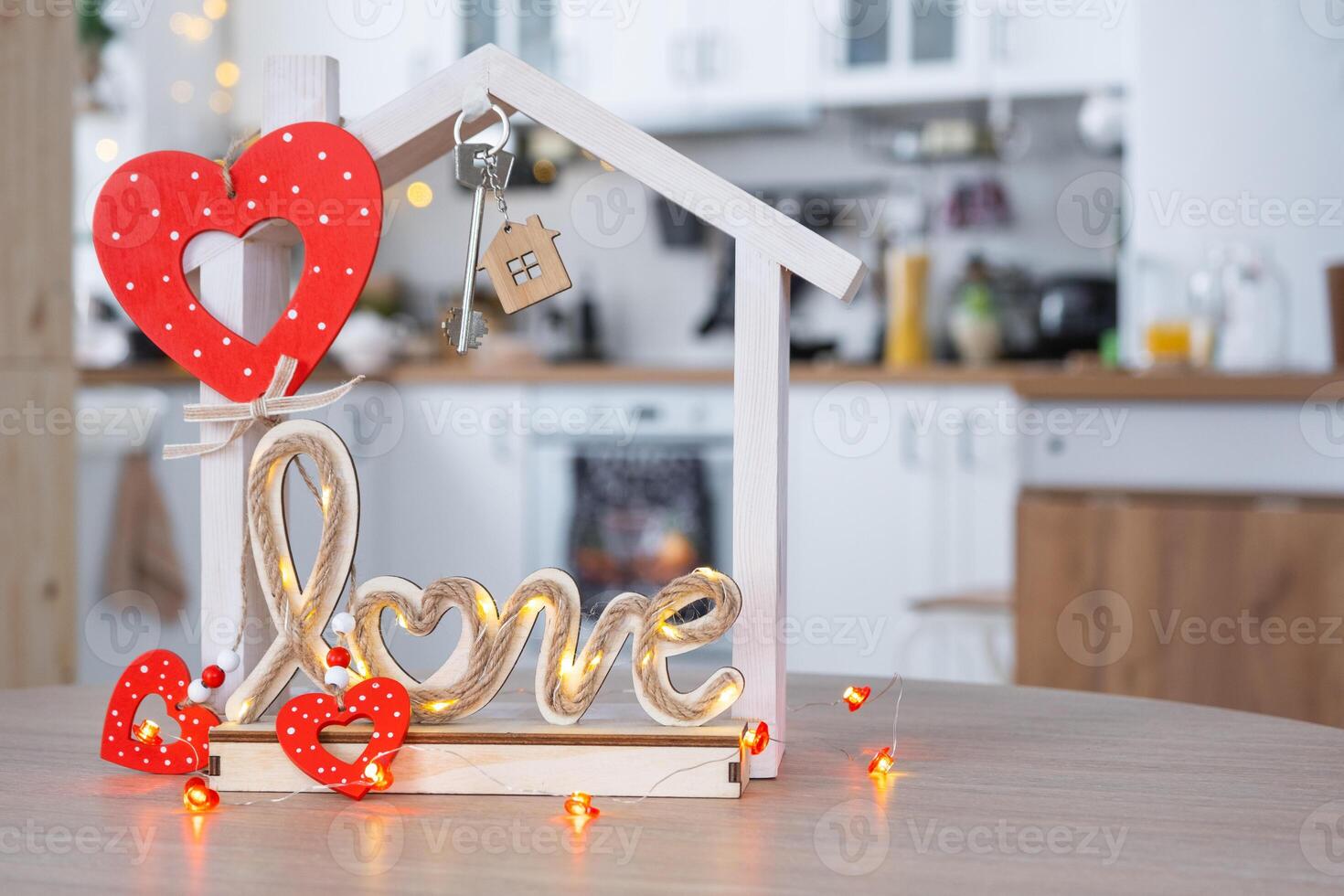 Key to tiny house of cozy home with Valentine decor on table of kitchen. Gift for valentines day, family love nest. design, project, moving to new house, mortgage, rent and purchase real estate photo