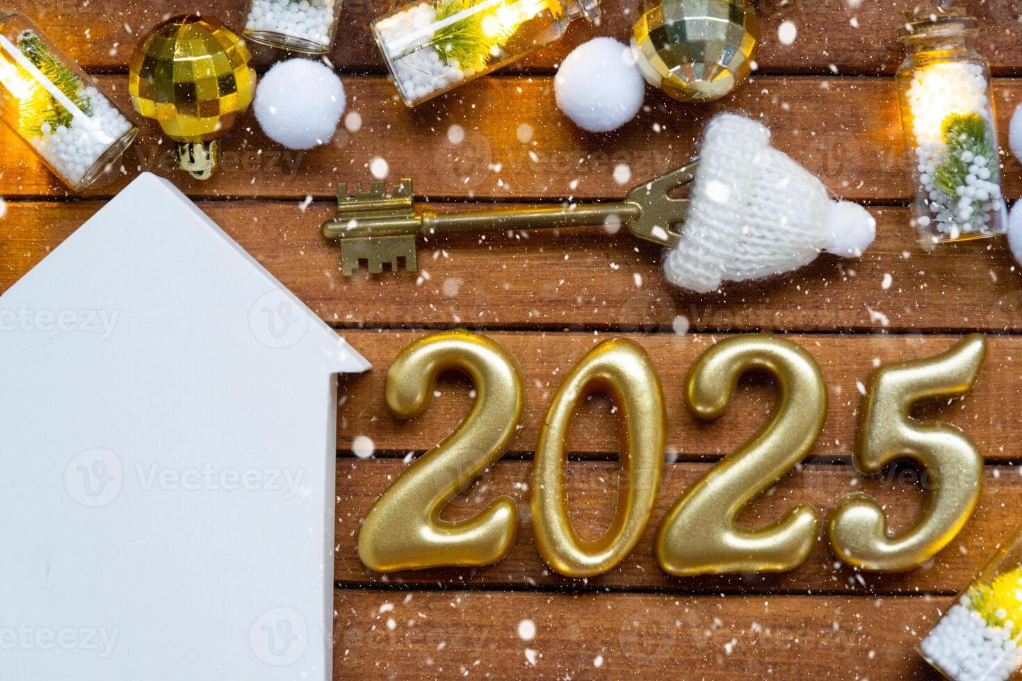 House key with tiny figure of home mock up on festive brown wooden background, lights of garlands. New Year 2025 wooden letters, greeting card. Purchase, construction, relocation, mortgage, insurance photo