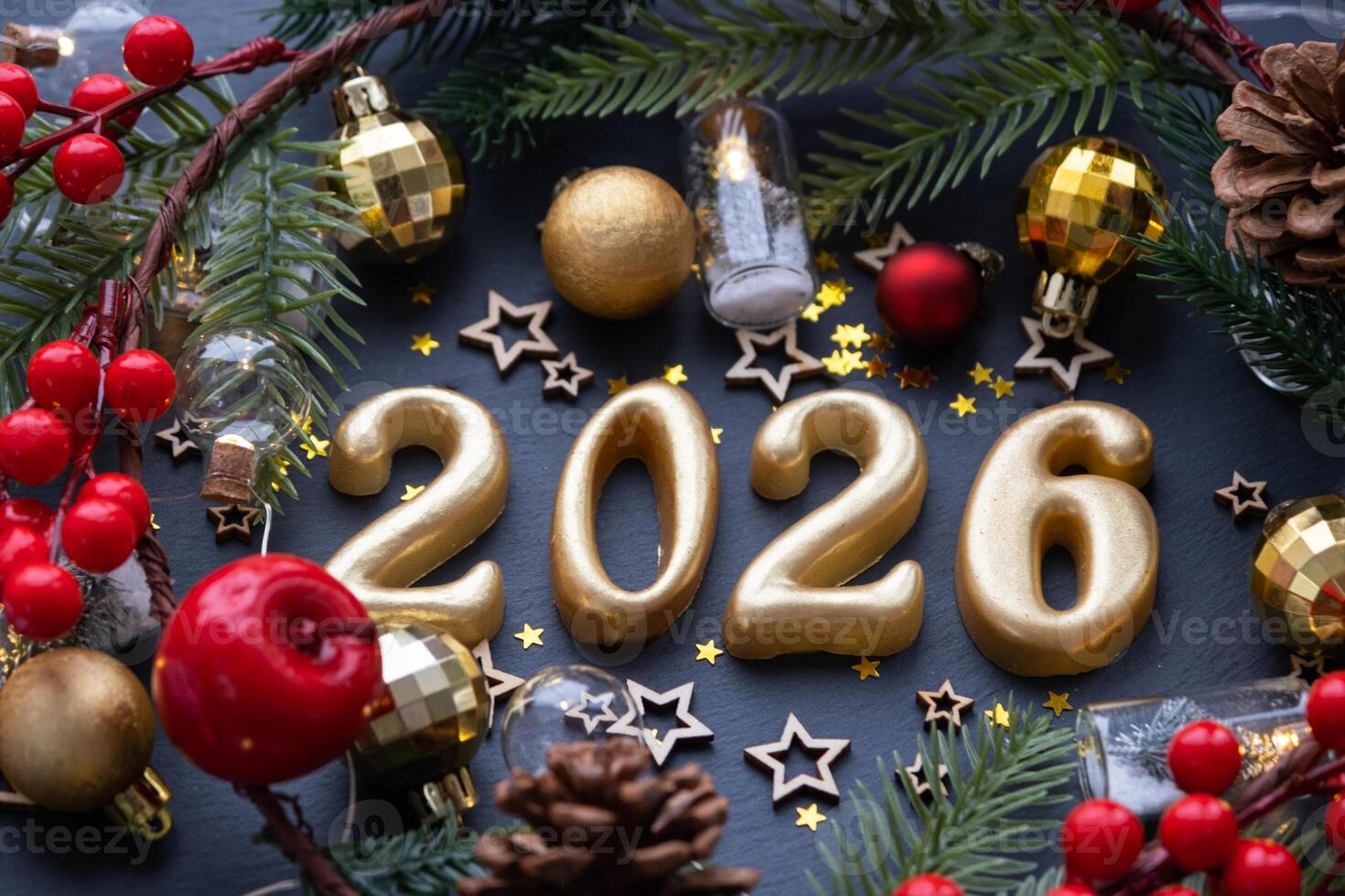 The golden figures 2026 made of candles on a black stone slate background are decorated with a festive decor of stars, sequins, fir branches, balls and garlands. Greeting card, happy New Year. photo