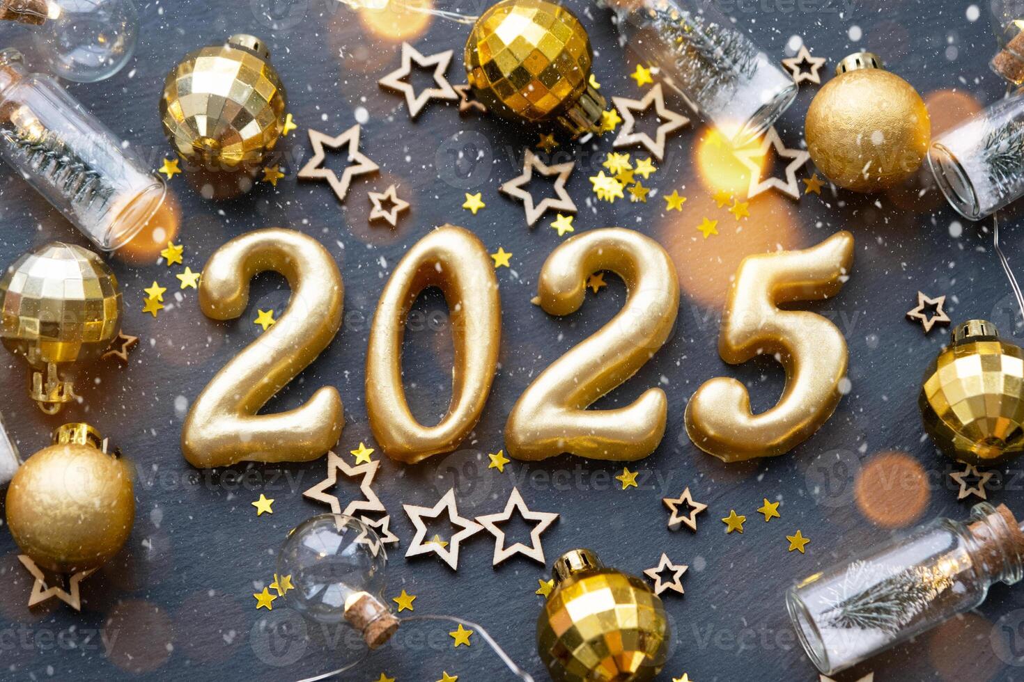 The golden figures 2025 made of candles on a black stone slate background are decorated with a festive decor of stars, sequins, fir branches, balls and garlands. Greeting card, happy New Year. photo