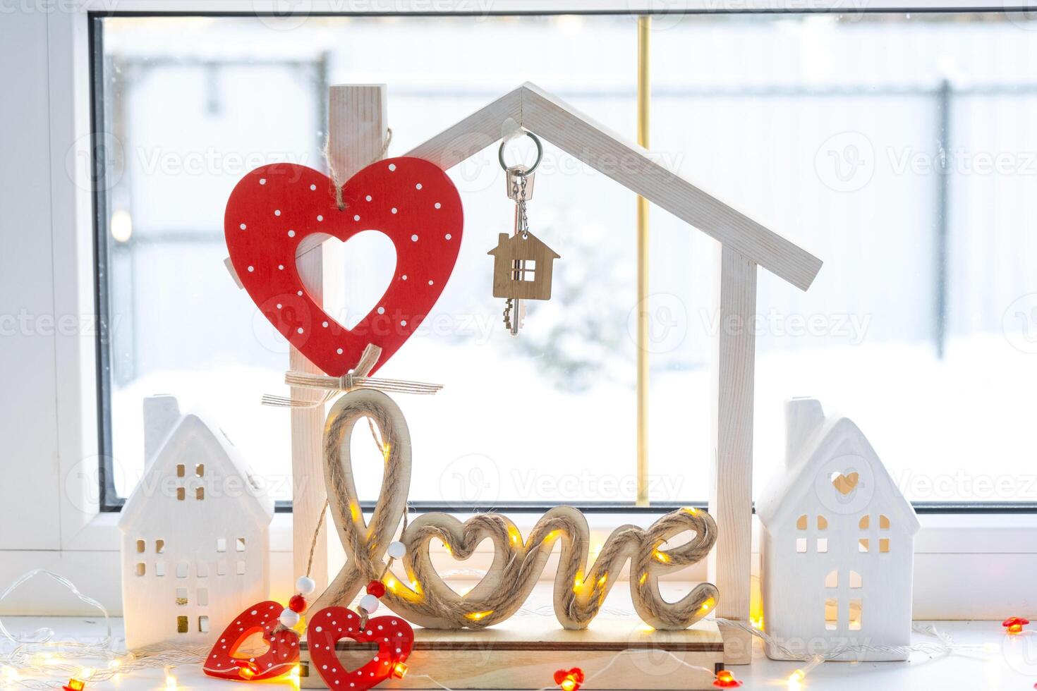 Key to tiny house of cozy home with Valentine decor on the windowsill. Gift for valentines day, family love nest. design, project, moving to new house, mortgage, rent and purchase real estate photo