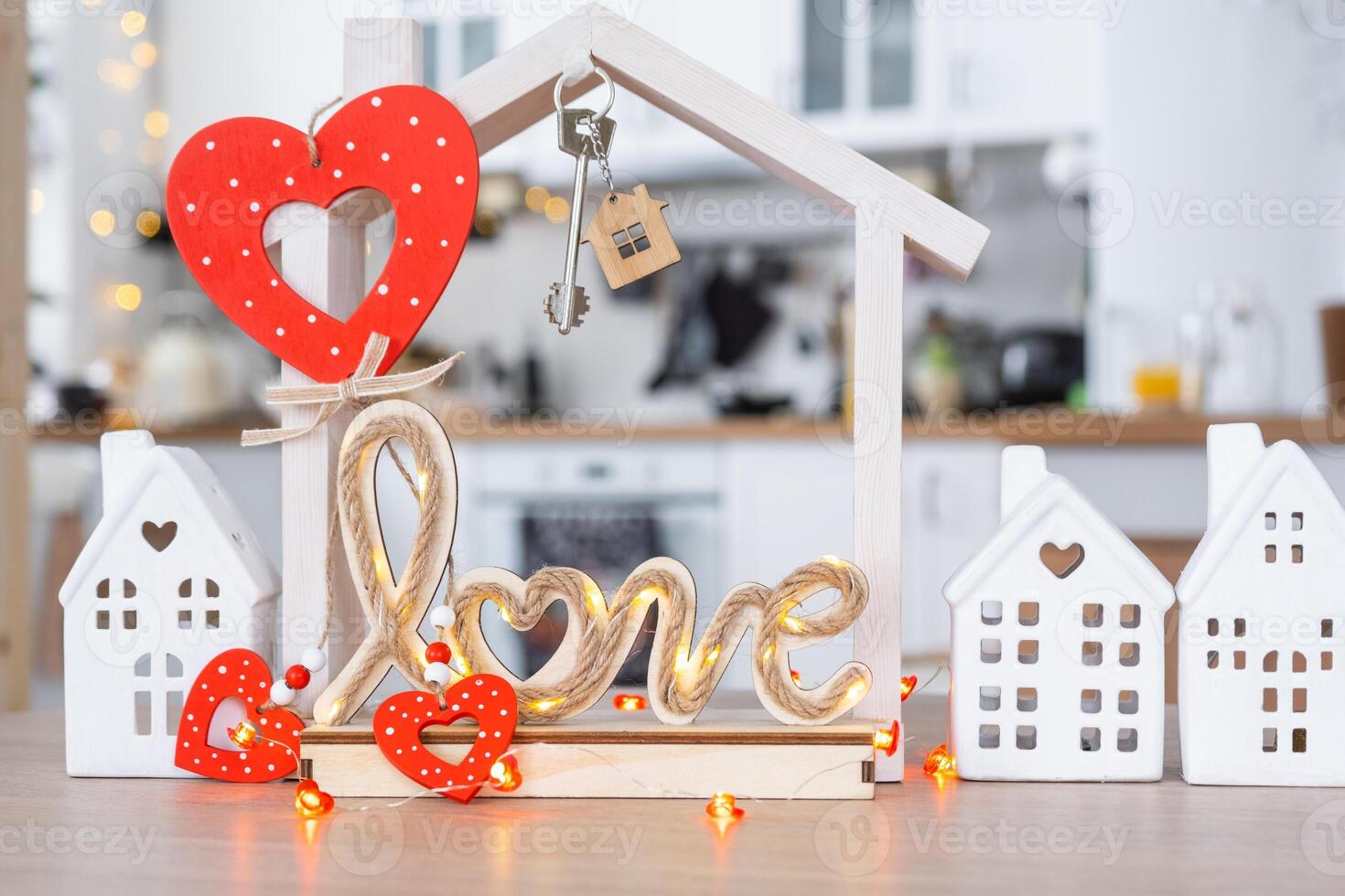 Key to tiny house of cozy home with Valentine decor on table of kitchen. Gift for valentines day, family love nest. design, project, moving to new house, mortgage, rent and purchase real estate photo