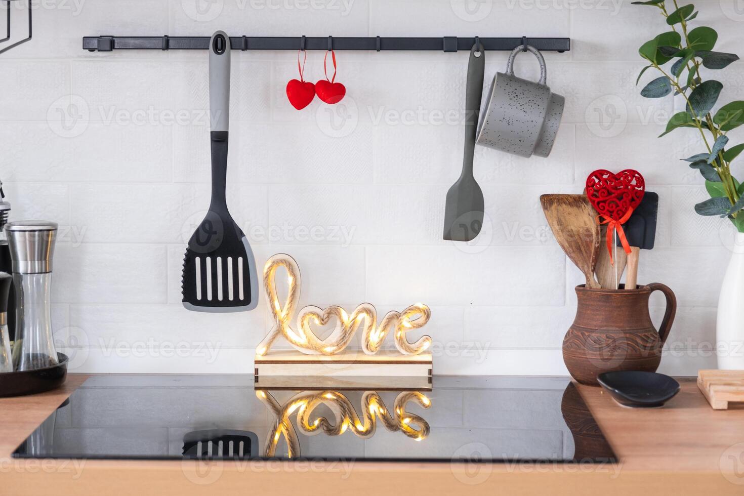 el interior de la cocina de la casa está decorado con corazones rojos para el día de san valentín. decoración en la mesa, estufa, utensilios, ambiente festivo en un nido familiar foto