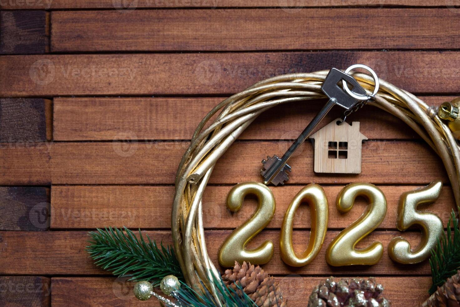 New Year House key with keychain cottage on festive brown wooden background with number 2025 in wreath, lights of garlands. Purchase, construction, relocation, mortgage, insurance photo
