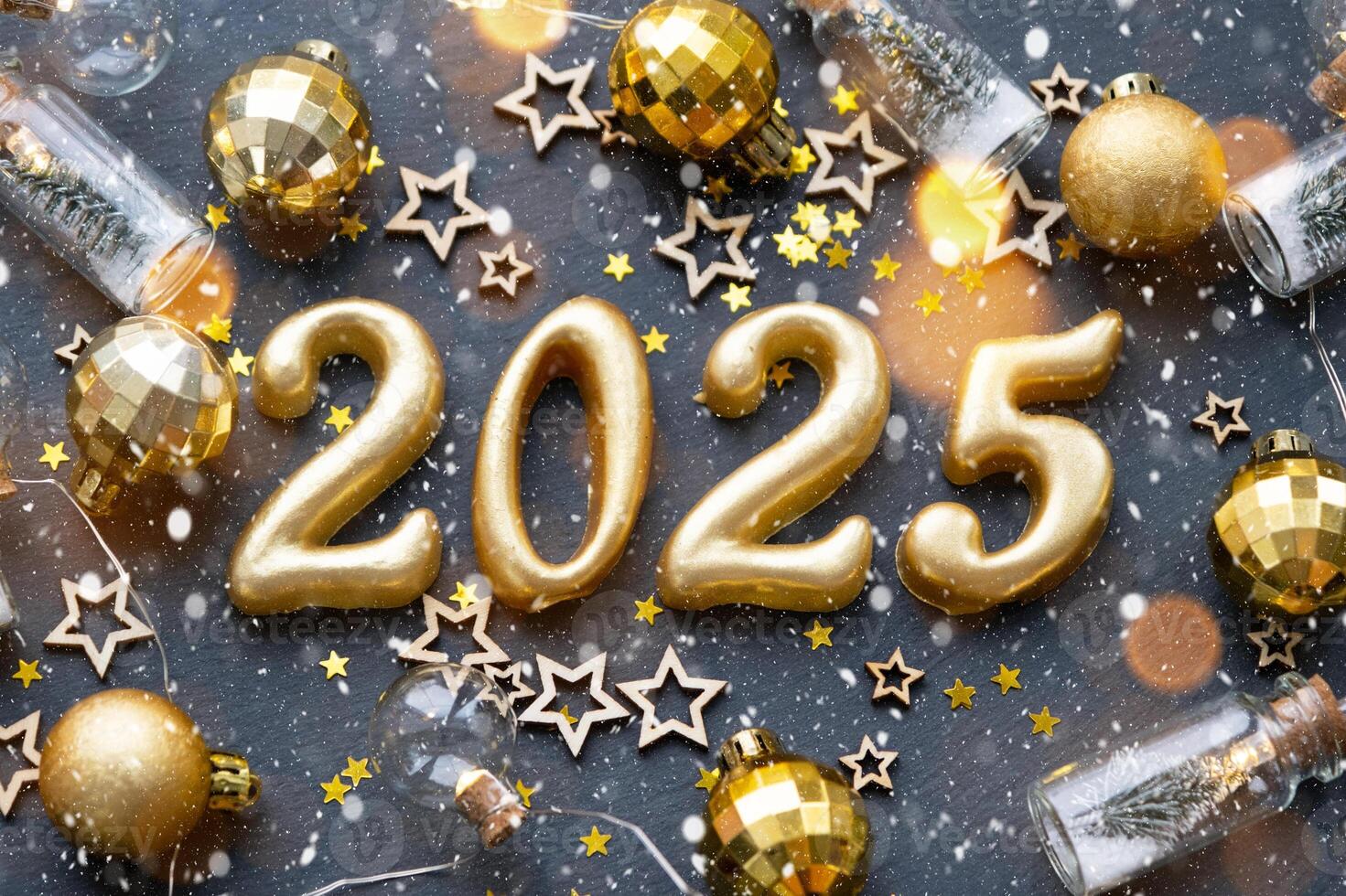 The golden figures 2025 made of candles on a black stone slate background are decorated with a festive decor of stars, sequins, fir branches, balls and garlands. Greeting card, happy New Year. photo