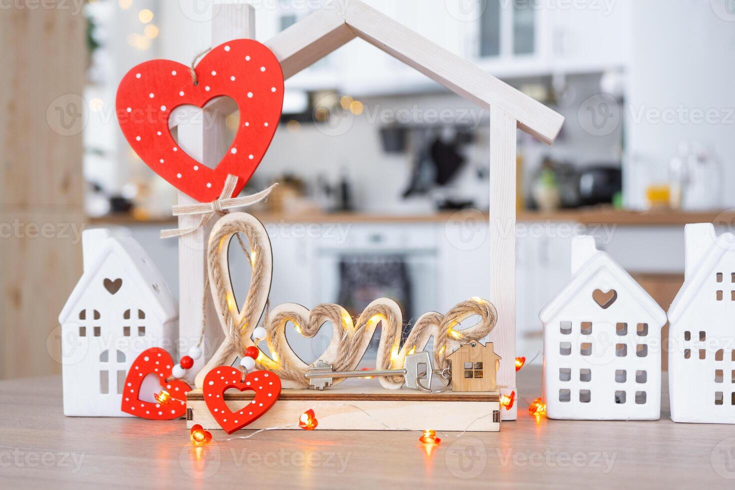 Key to tiny house of cozy home with Valentine decor on table of kitchen. Gift for valentines day, family love nest. design, project, moving to new house, mortgage, rent and purchase real estate photo