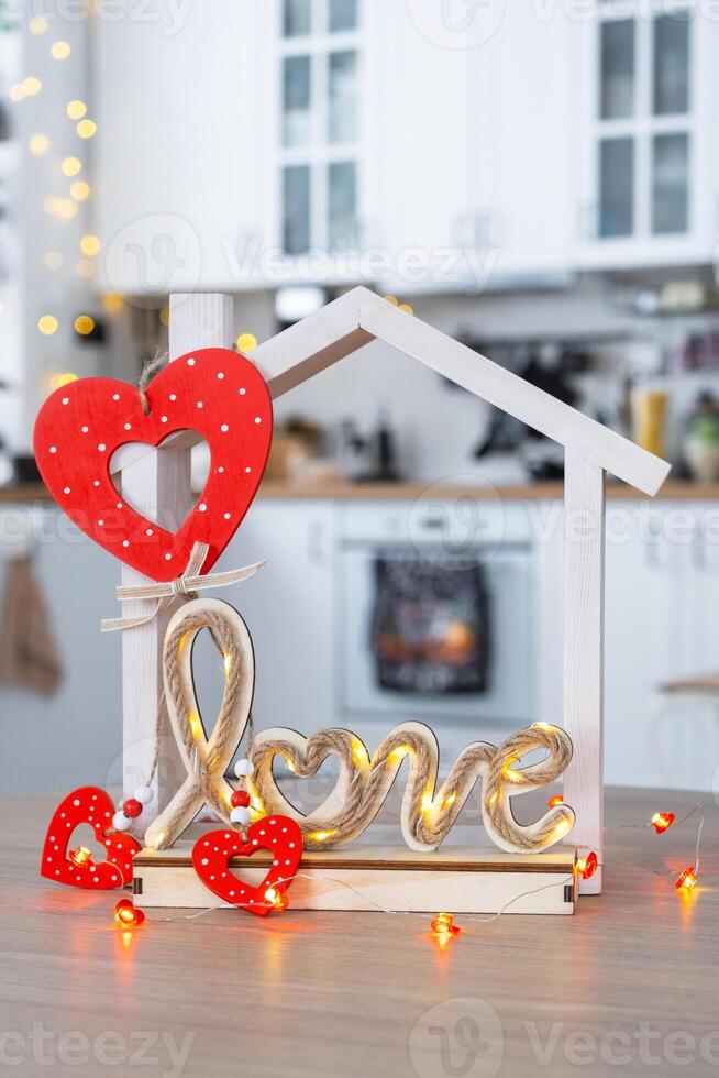 Key to tiny house of cozy home with Valentine decor on table of kitchen. Gift for valentines day, family love nest. design, project, moving to new house, mortgage, rent and purchase real estate photo