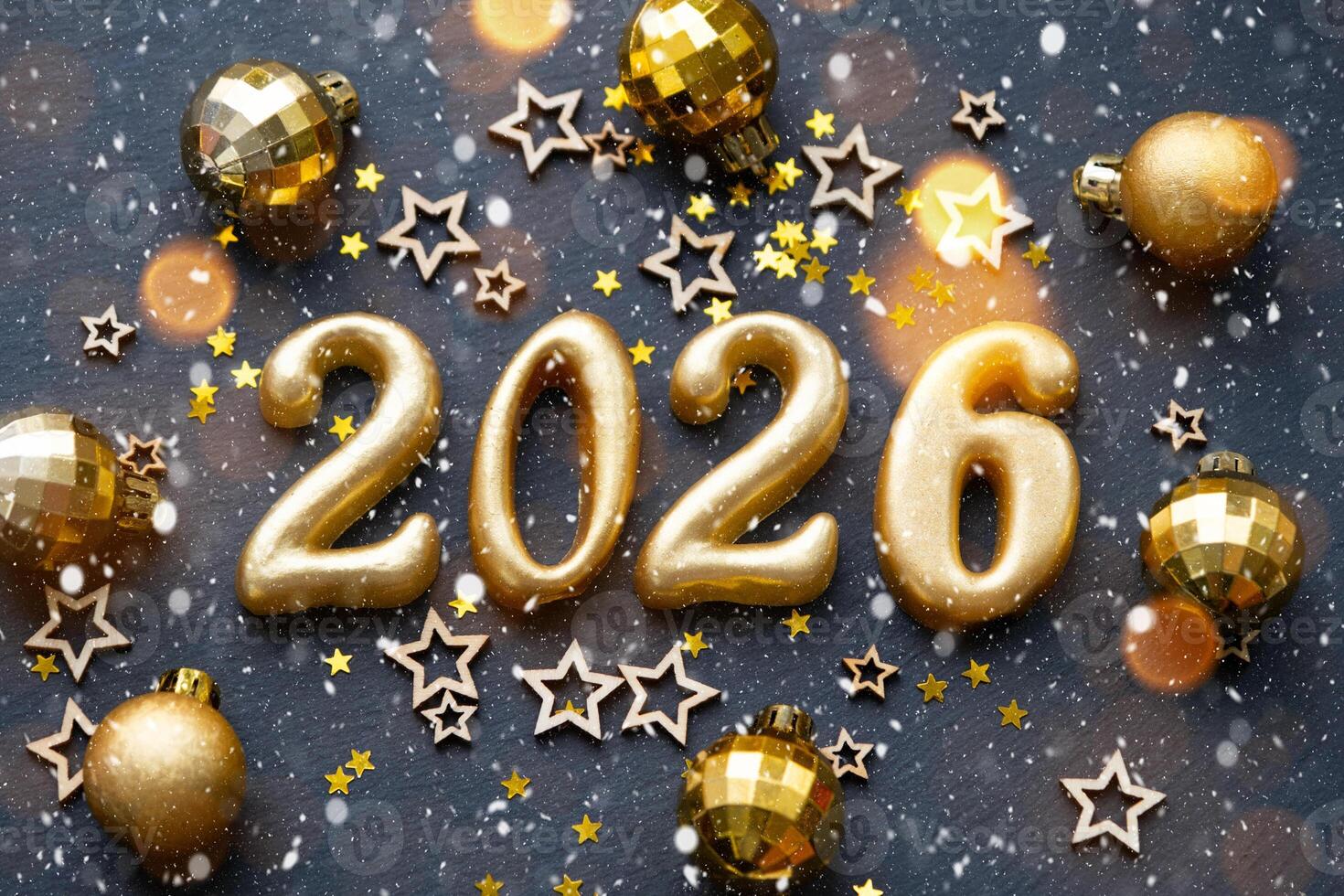 The golden figures 2026 made of candles on a black stone slate background are decorated with a festive decor of stars, sequins, fir branches, balls and garlands. Greeting card, happy New Year. photo