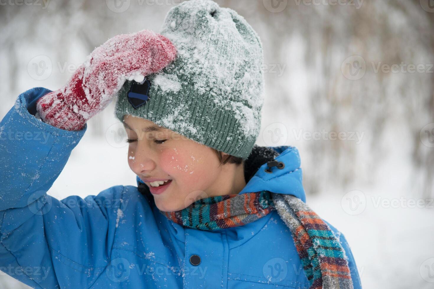 A boy in a snowy park. Photo of a teenager in a winter forest. Winter, winter holidays, vacations, vacations.
